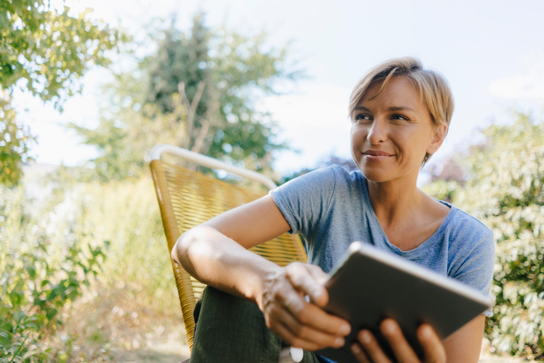 woman smiling while sitting outside reading