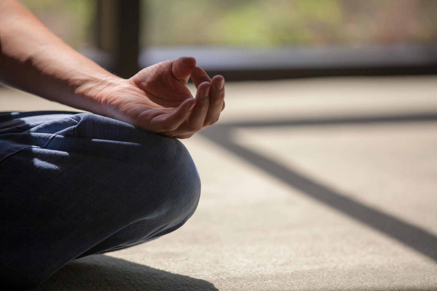 Close-up of hand in meditation position on leg.