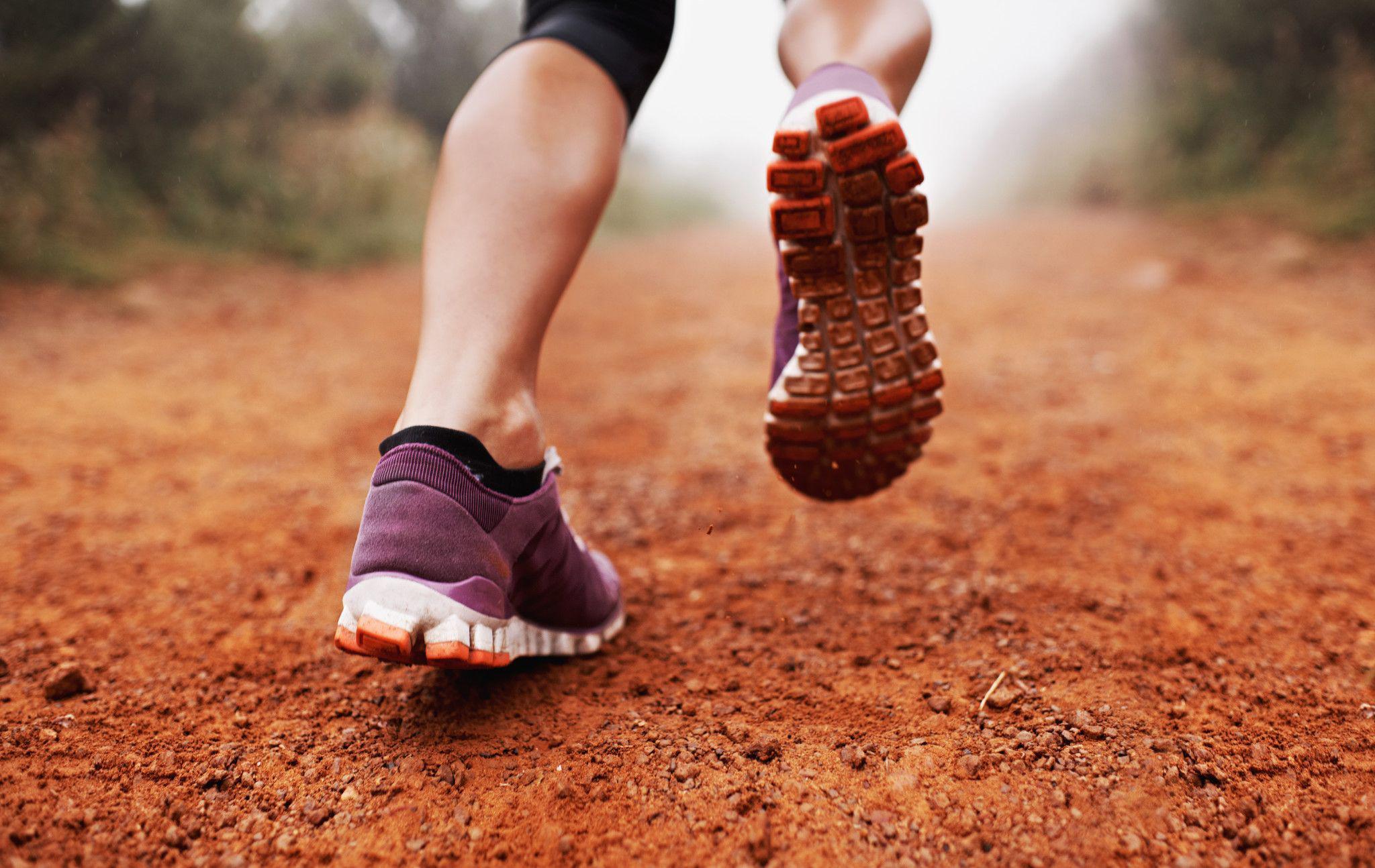 close-up of woman's feet running on red dirt