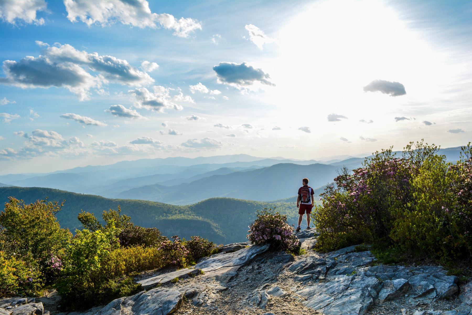 A man on a hike taking a break to look out at the view.