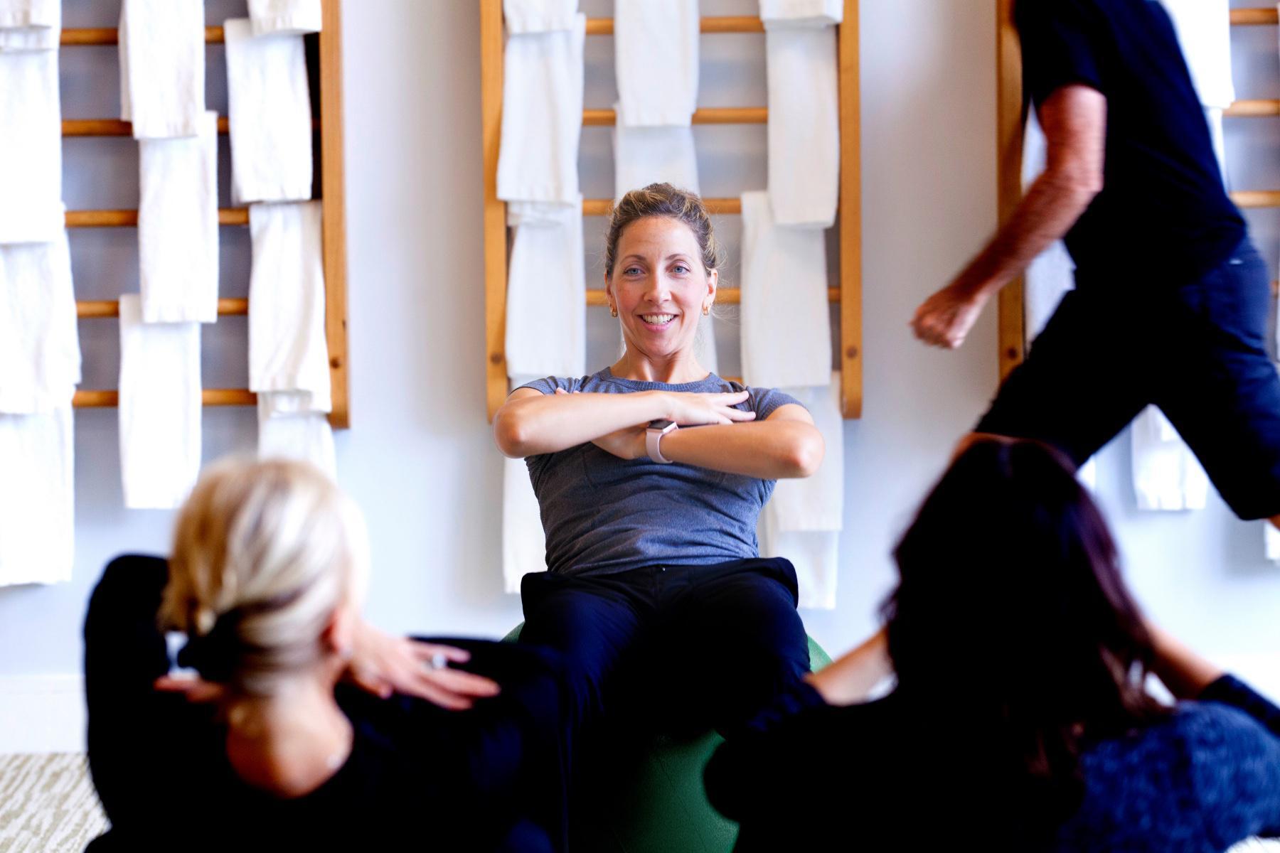female fitness instructor showing class how to do crunches on workout ball