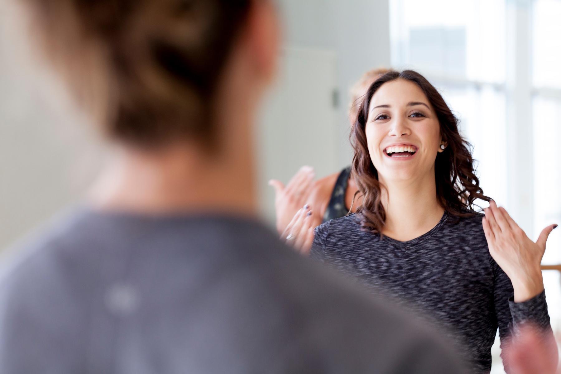 close-up of young woman's smiling face in a workout class with blurred people in foreground and background