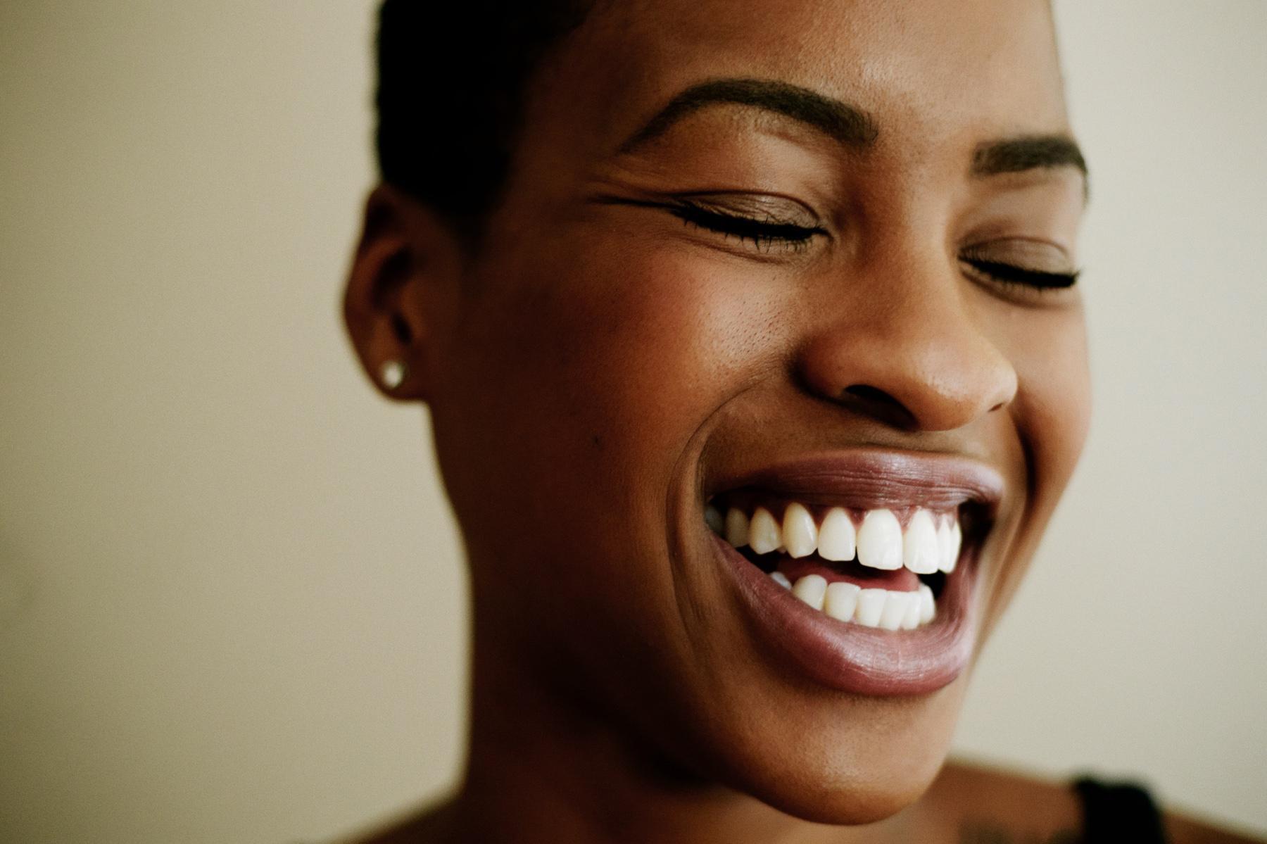 Close-up of woman smiling while looking off to the side with eyes closed.