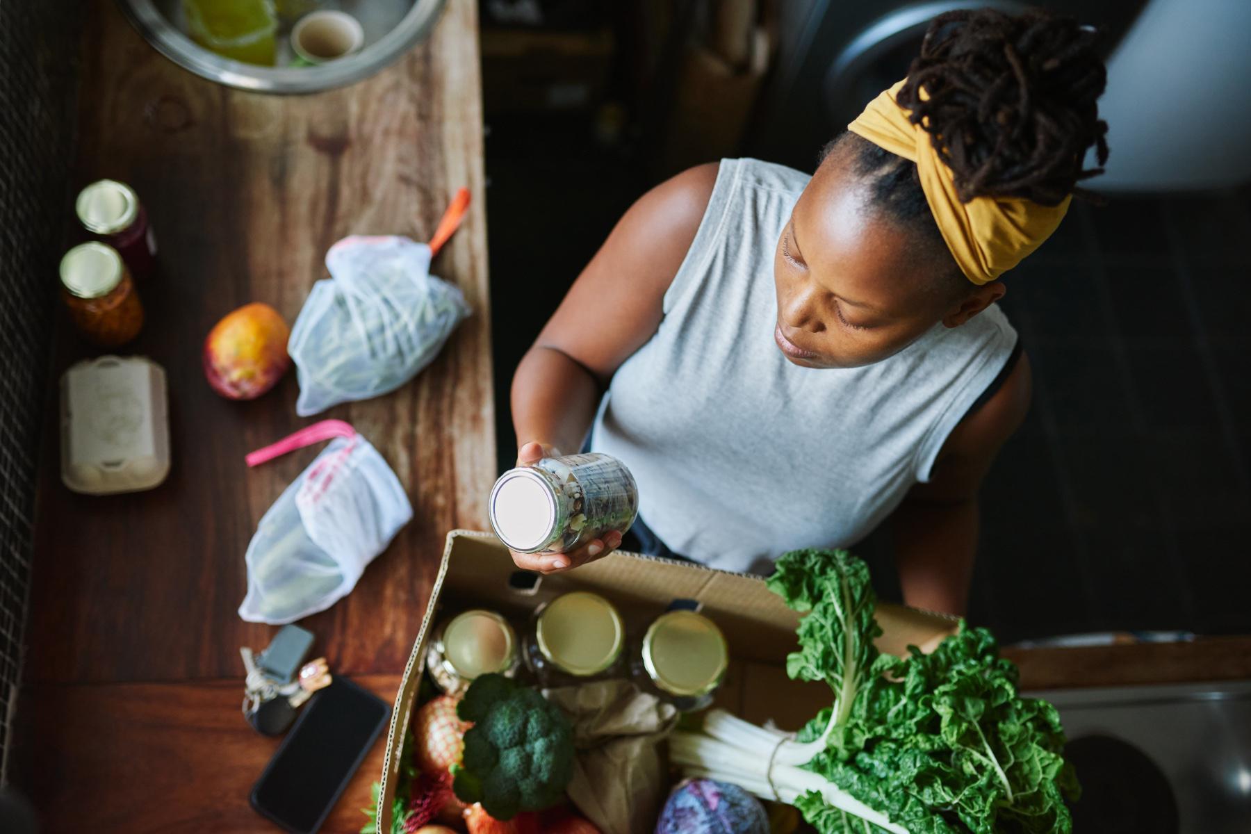 Overhead shot of woman reading food label on jar.