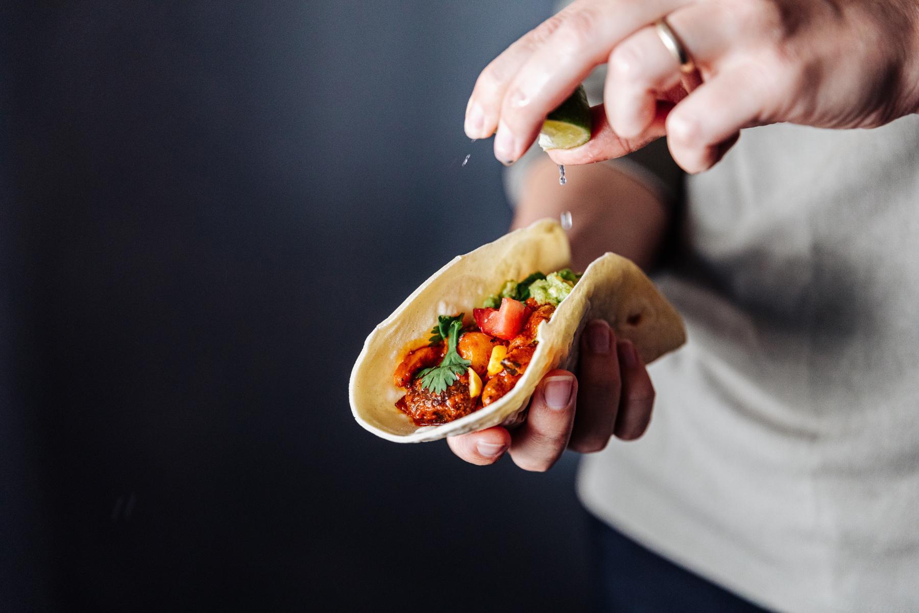 close-up of hand squeezing lime on a taco
