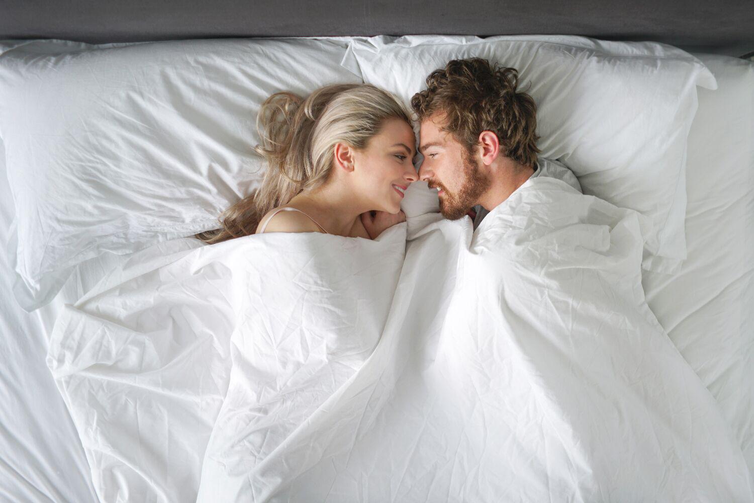 a couple covered by sheets in a bed
