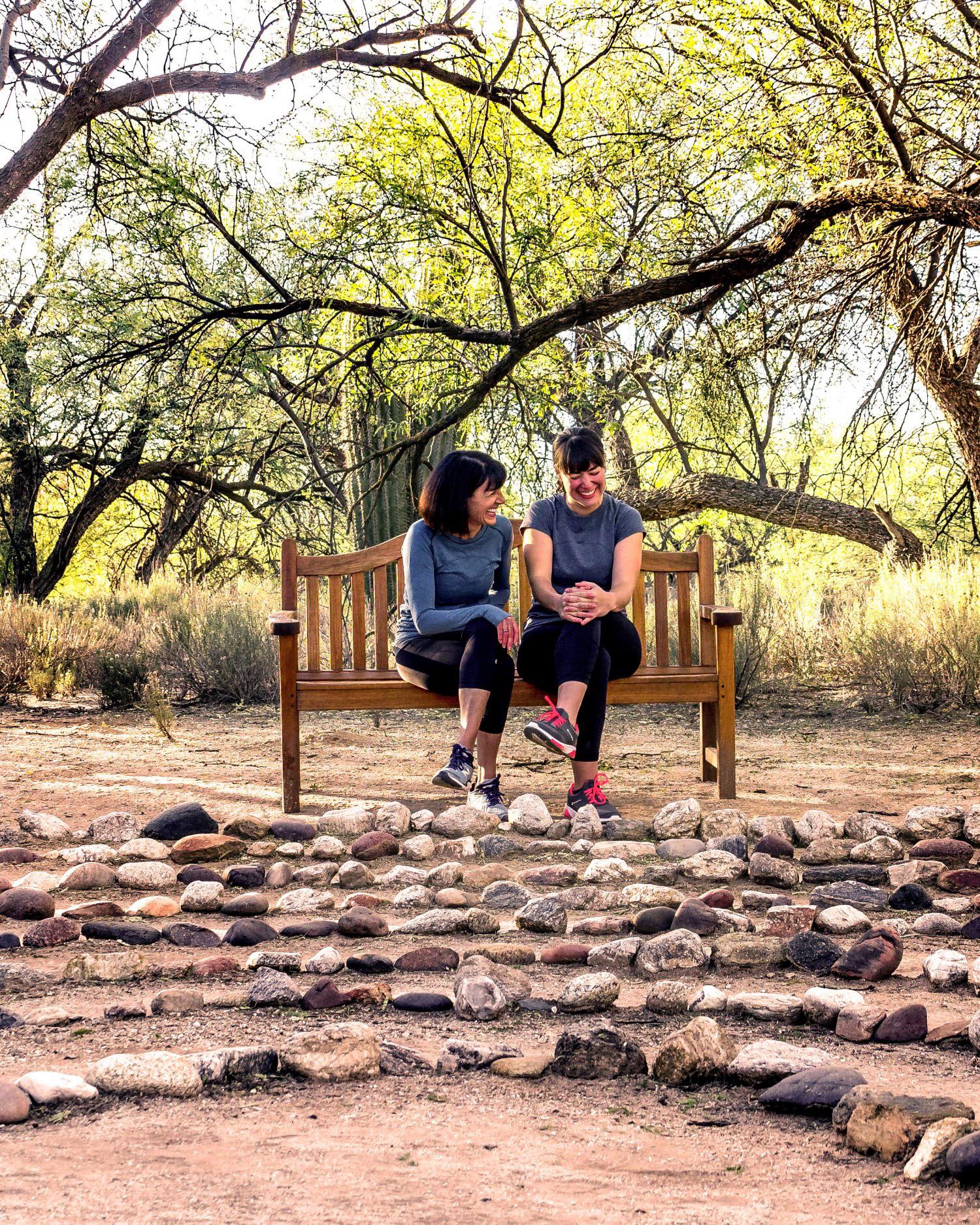 A mother and daughter sitting on a bench next to the labyrinth.