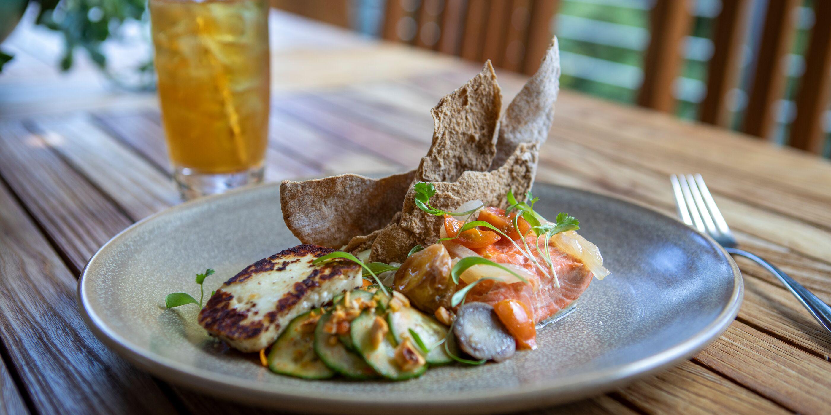 A plate of salmon and vegetables paired with a glass of herbal tea at Canyon Ranch Woodside Health Spa Resort outdoor deck restaurant.