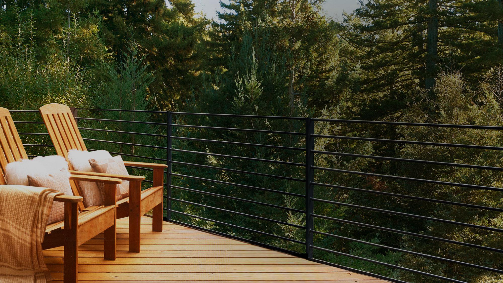 A young woman sitting on a brown leather sofa. She is surrounded by windows that look out at a sea of trees. 