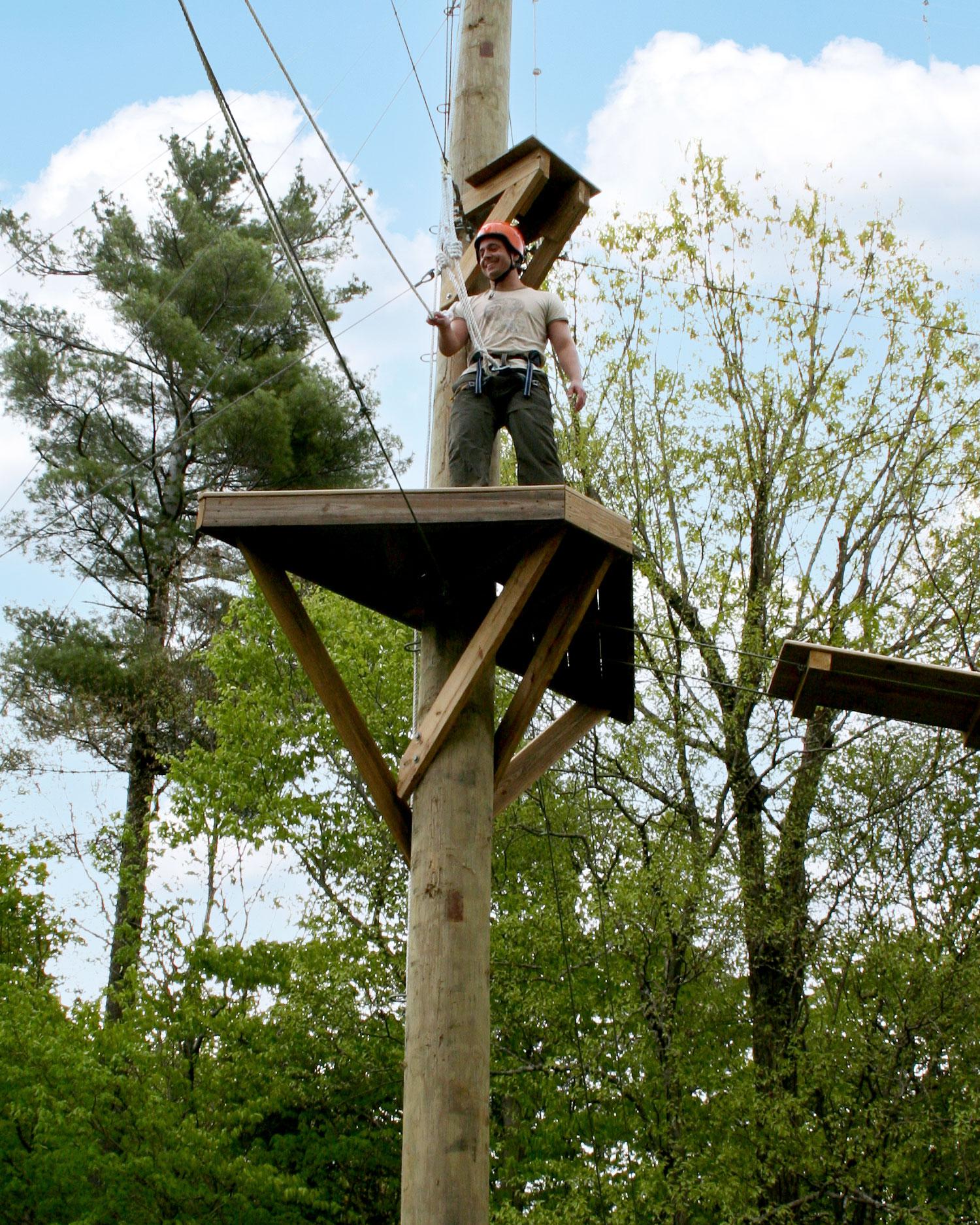 Man zip lining on high ropes course.