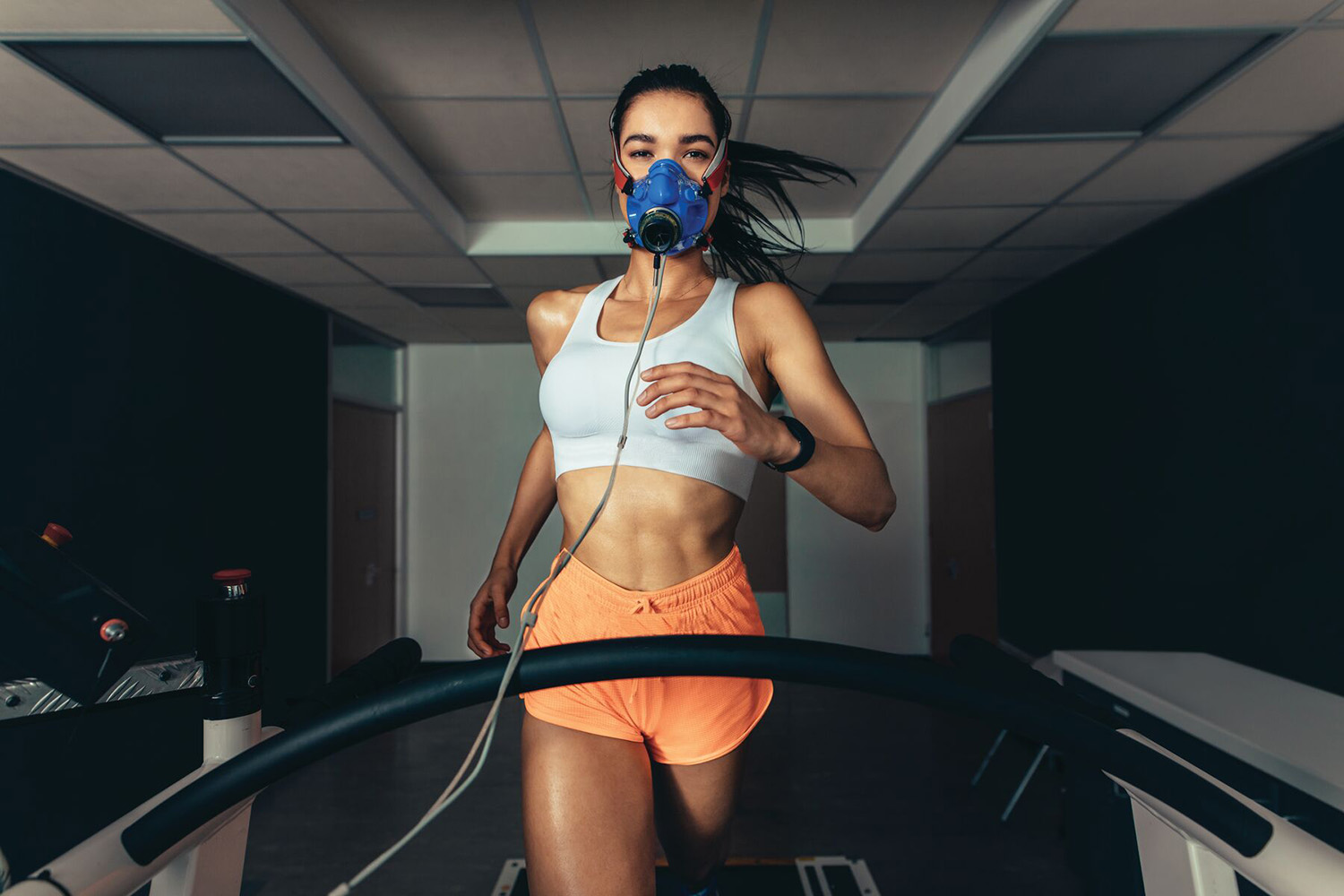a woman running on a treadmill in a vo2 max mask