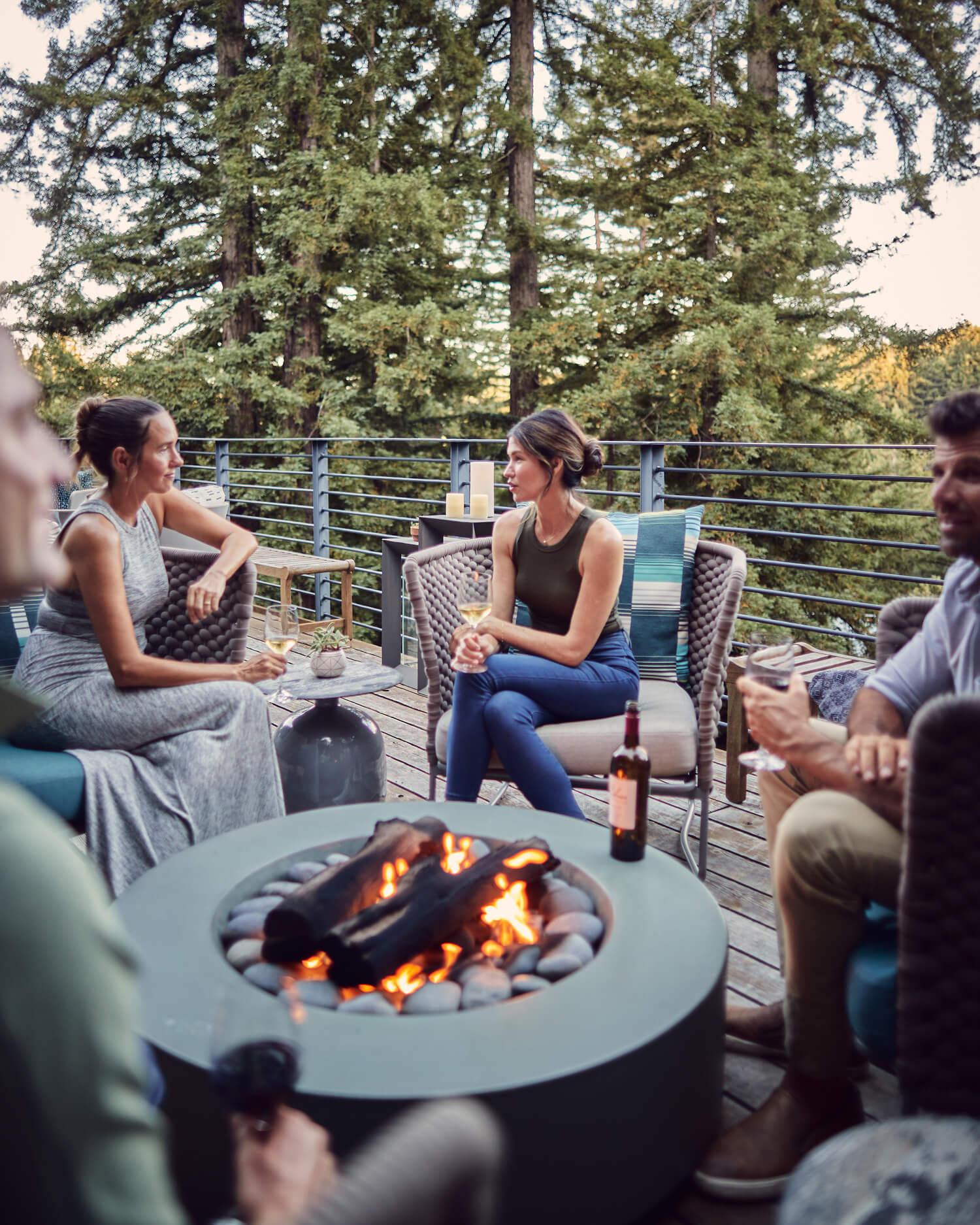A group outdoors on a deck by a firepit