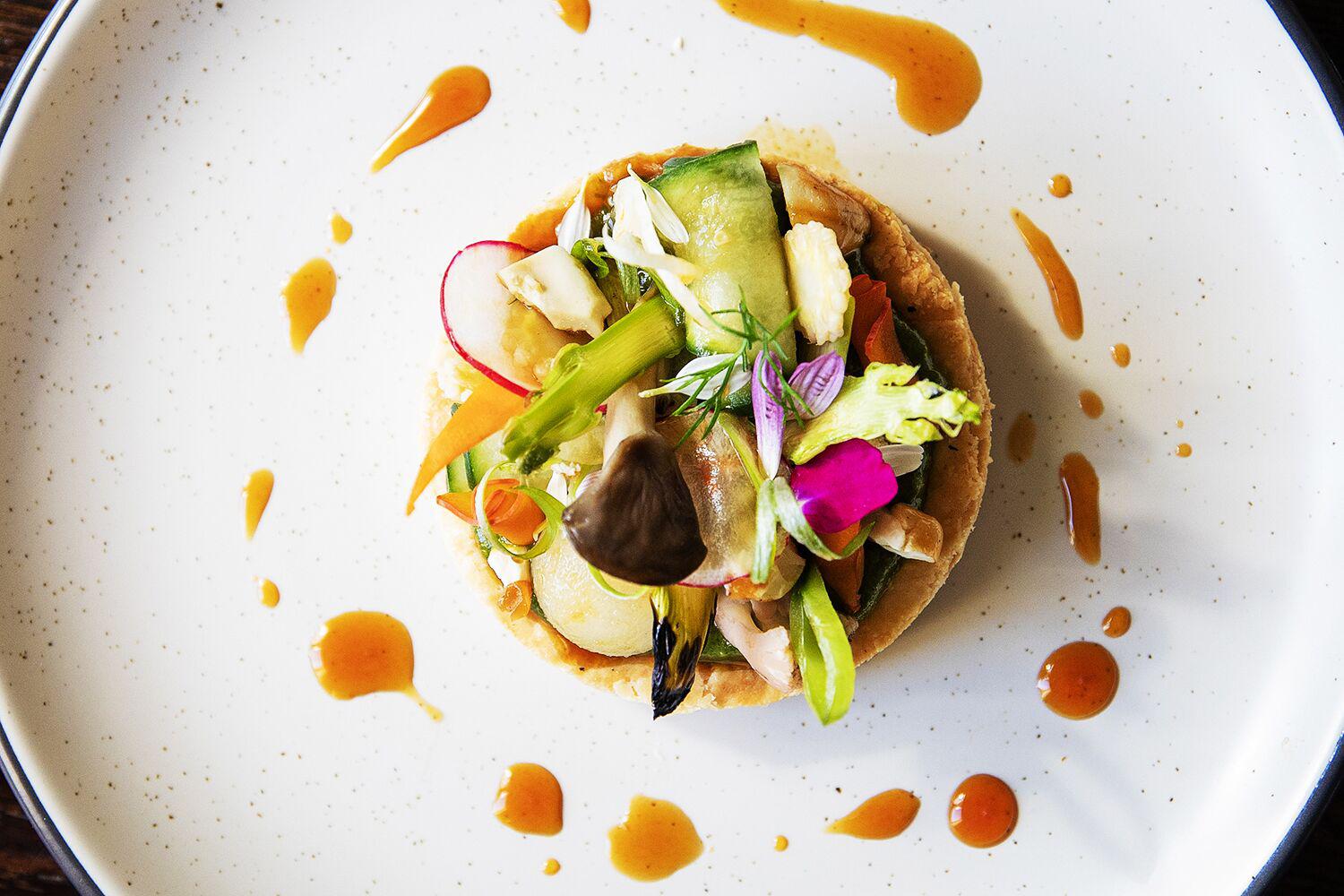 Mixed veg crudo with artistic sauce display on white speckled plate