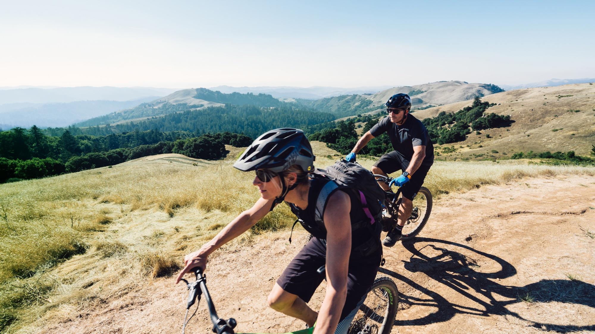 Two people mountain biking together surrounded by moutains