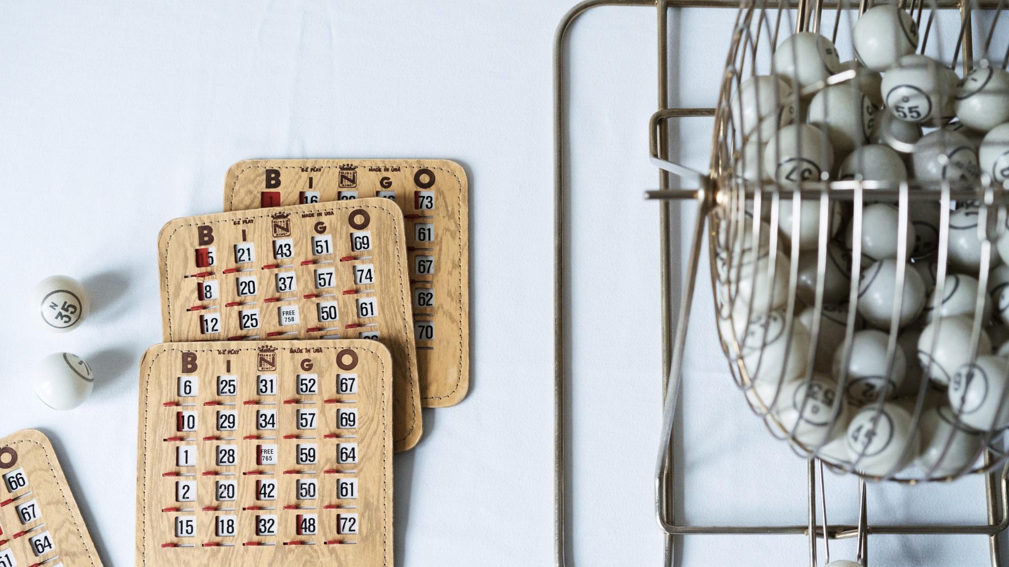 Bingo cage filled with bingo balls next to bingo cards