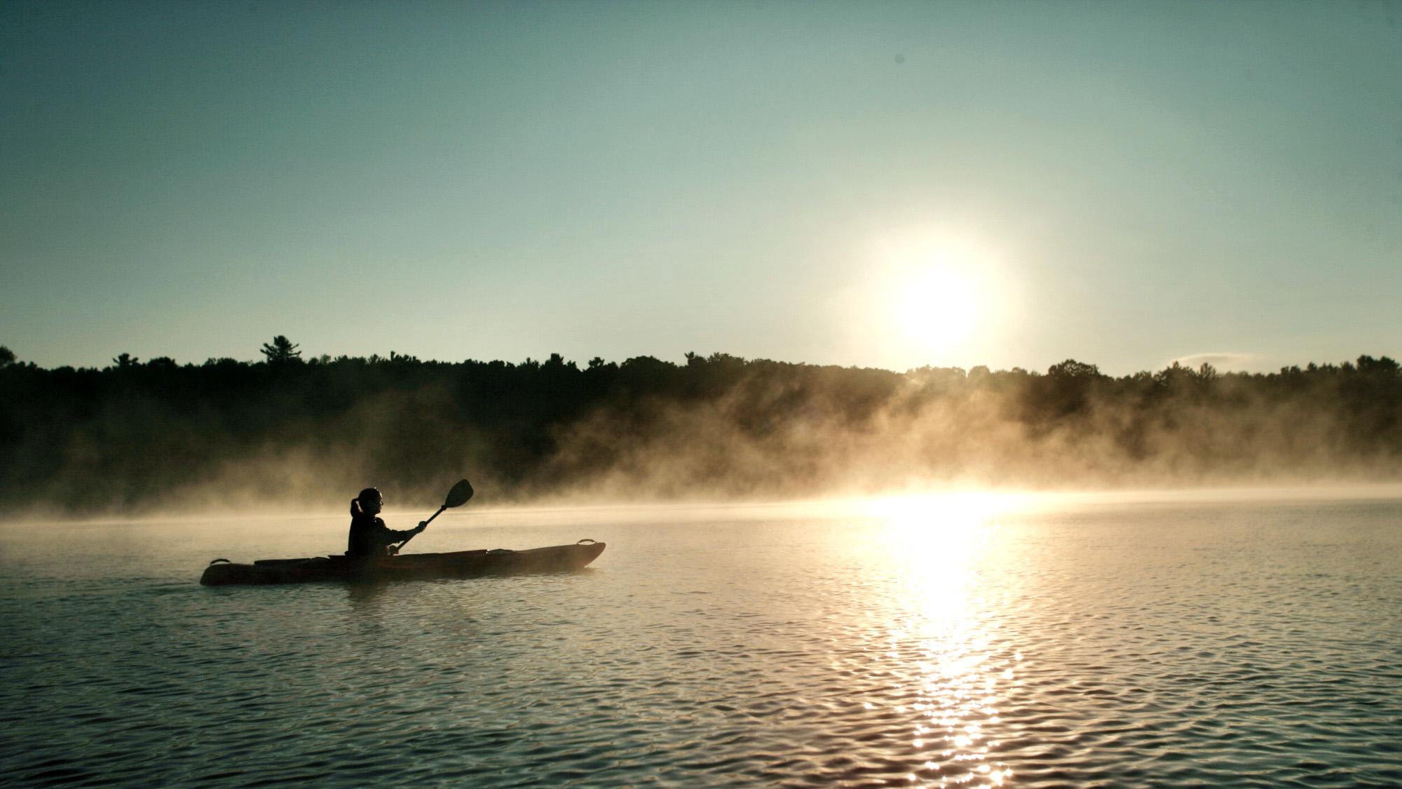 Woman kayaking solo at sunrise.