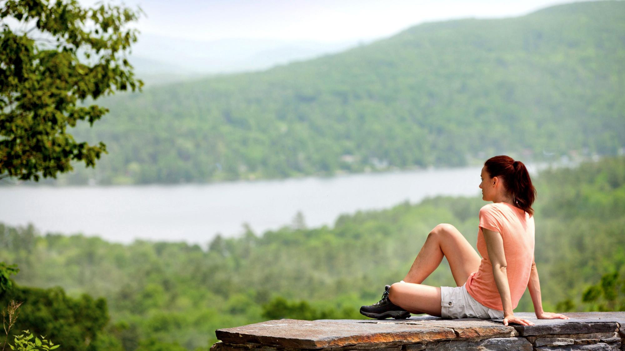 Woman sitting overlooking beautiful lake and trees.