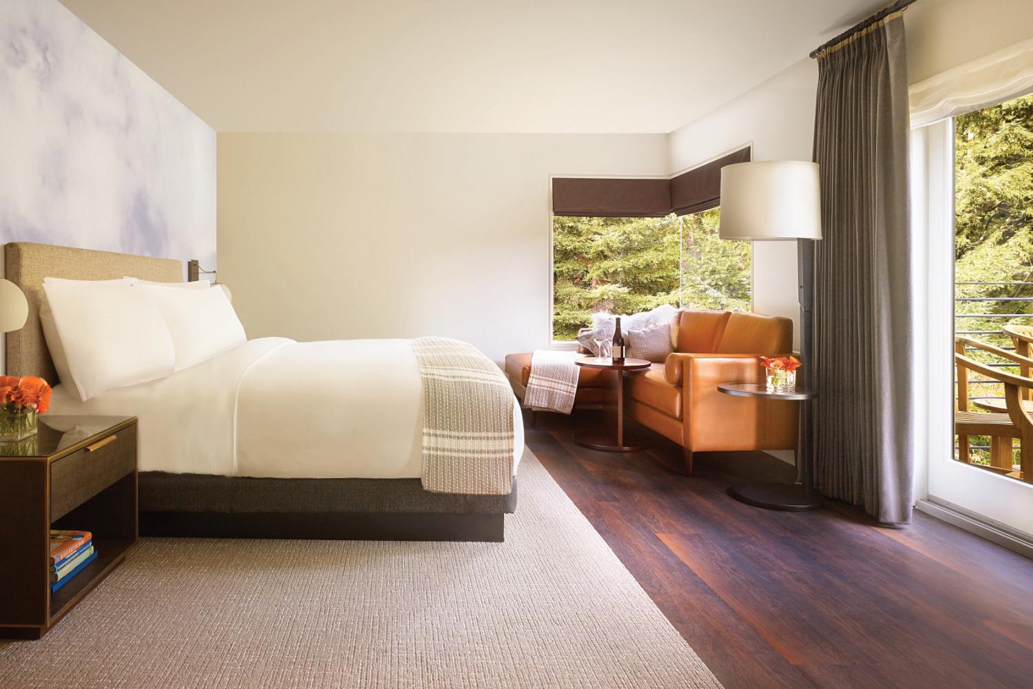 A bedroom with a white linen-covered bed and wooden nightstand 