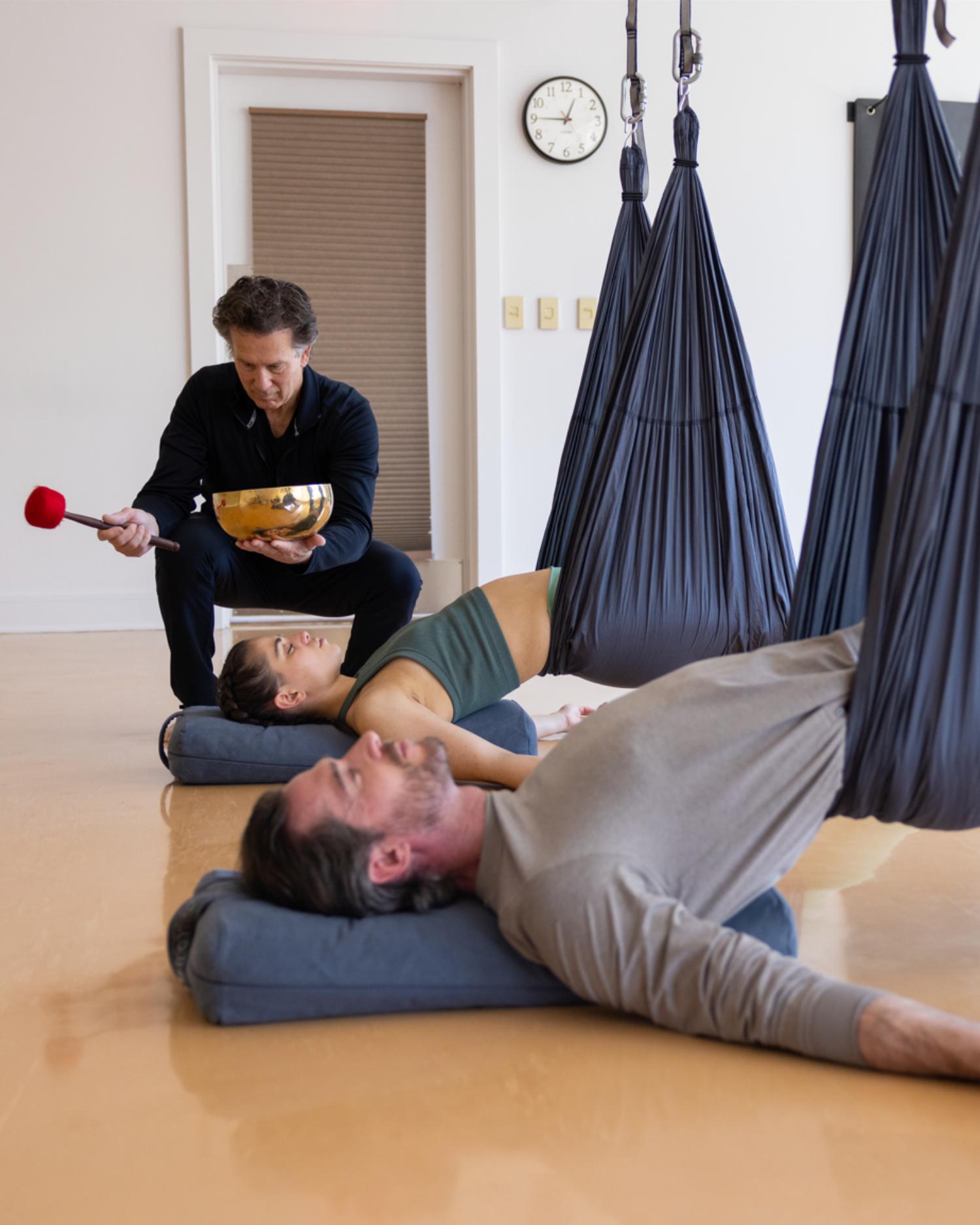 An group having an aerial yoga sound healing experience