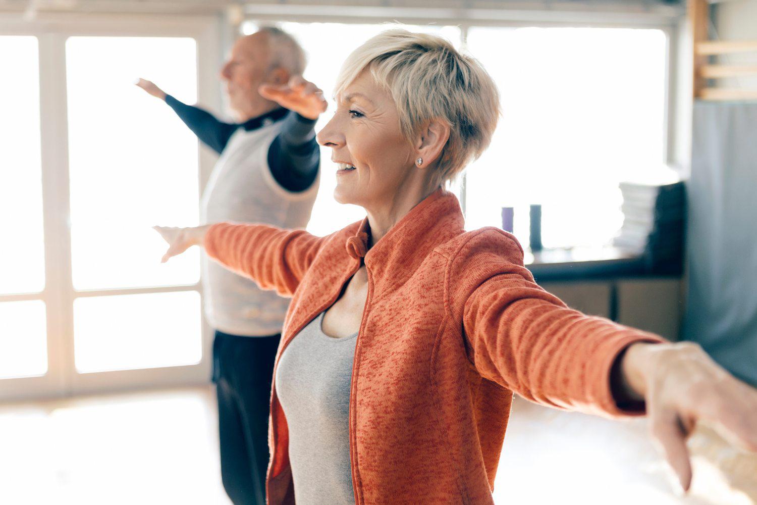 Close-up of a man and woman stretching their arms out to the  side during a fitness class at Canyon Ranch Fitness + Spa Resort