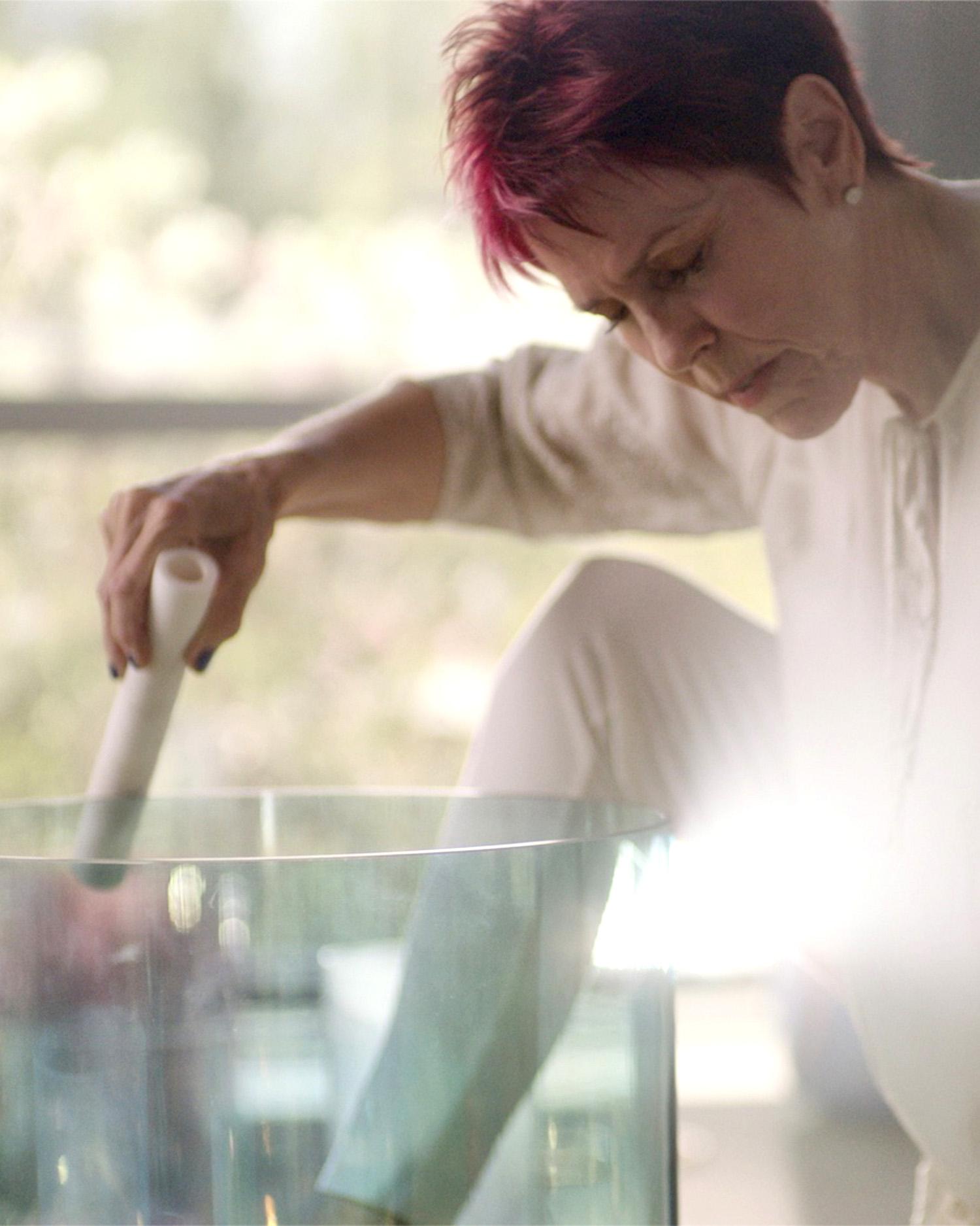 Close-up image of woman using a crystal healing bowl.