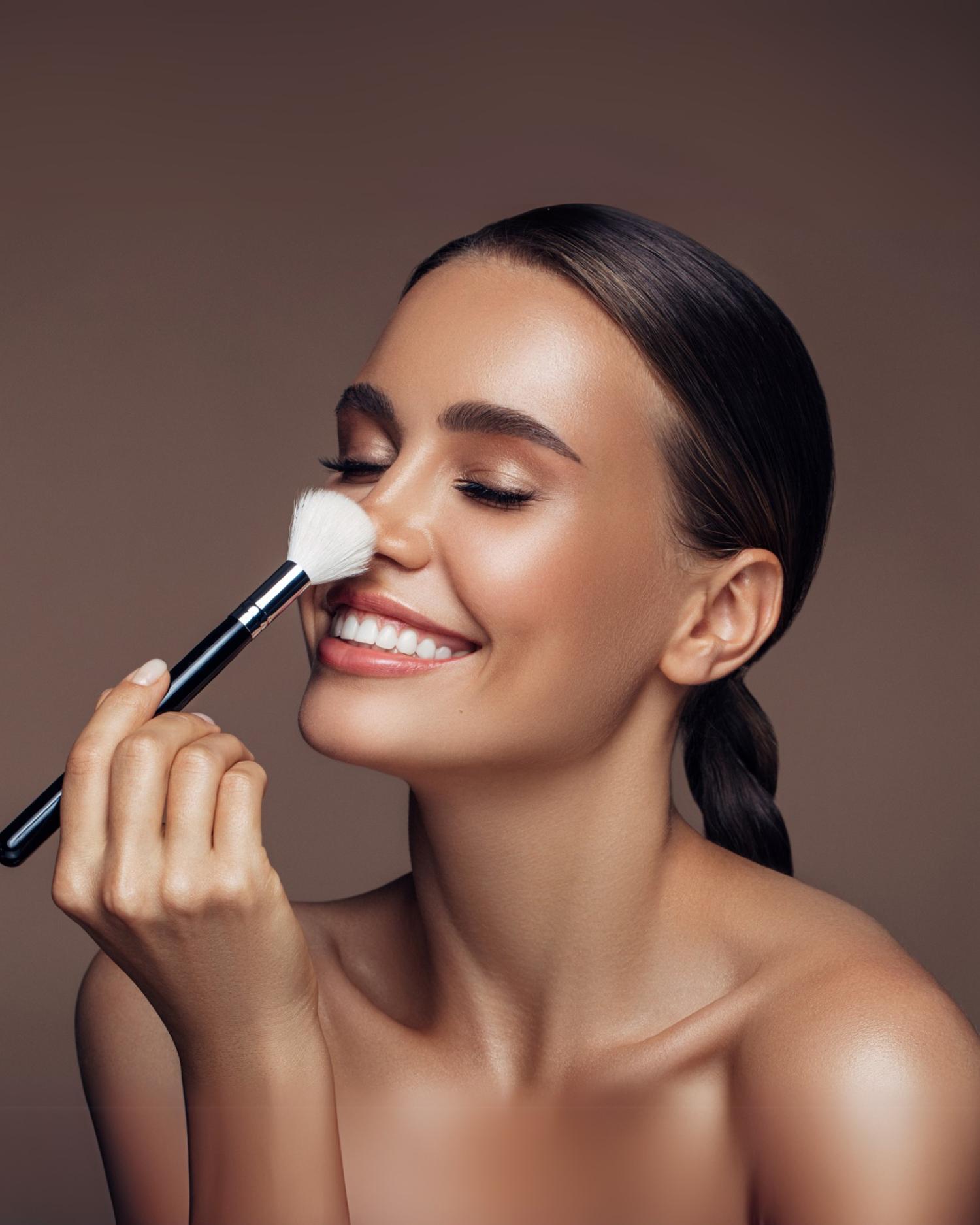 A woman brushing her nose with a make up brush. 