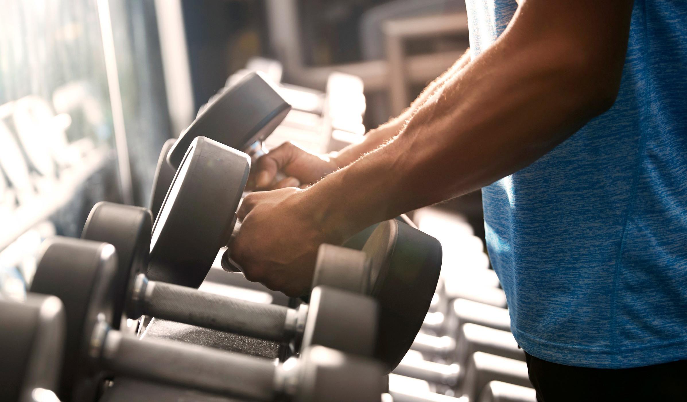 Close-up image of man lifting weights off rack.