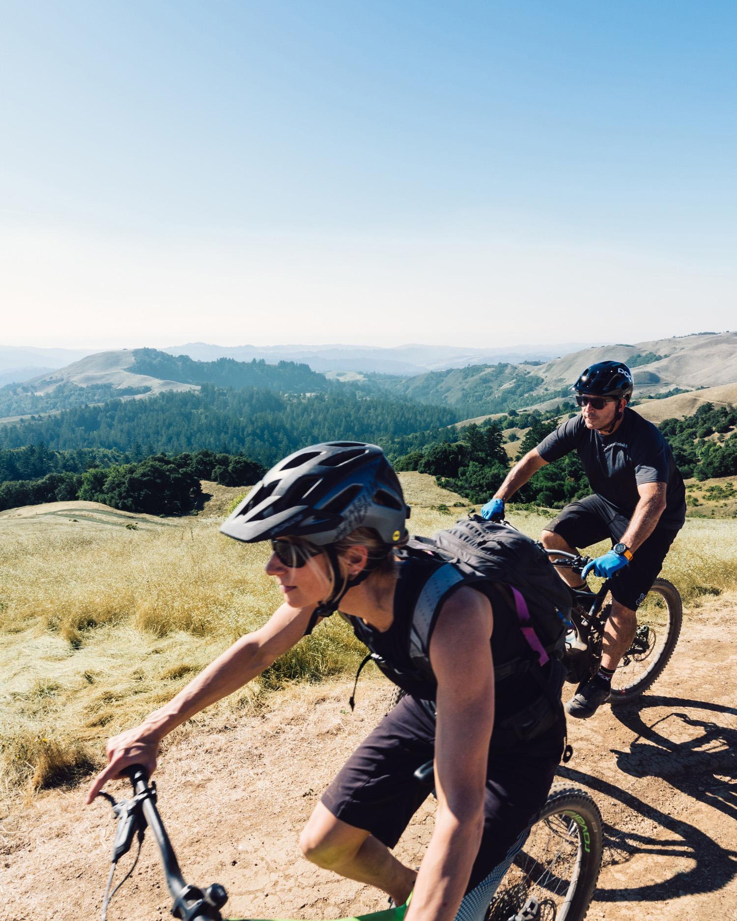 Image of man and woman on mountain bikes on hillside.