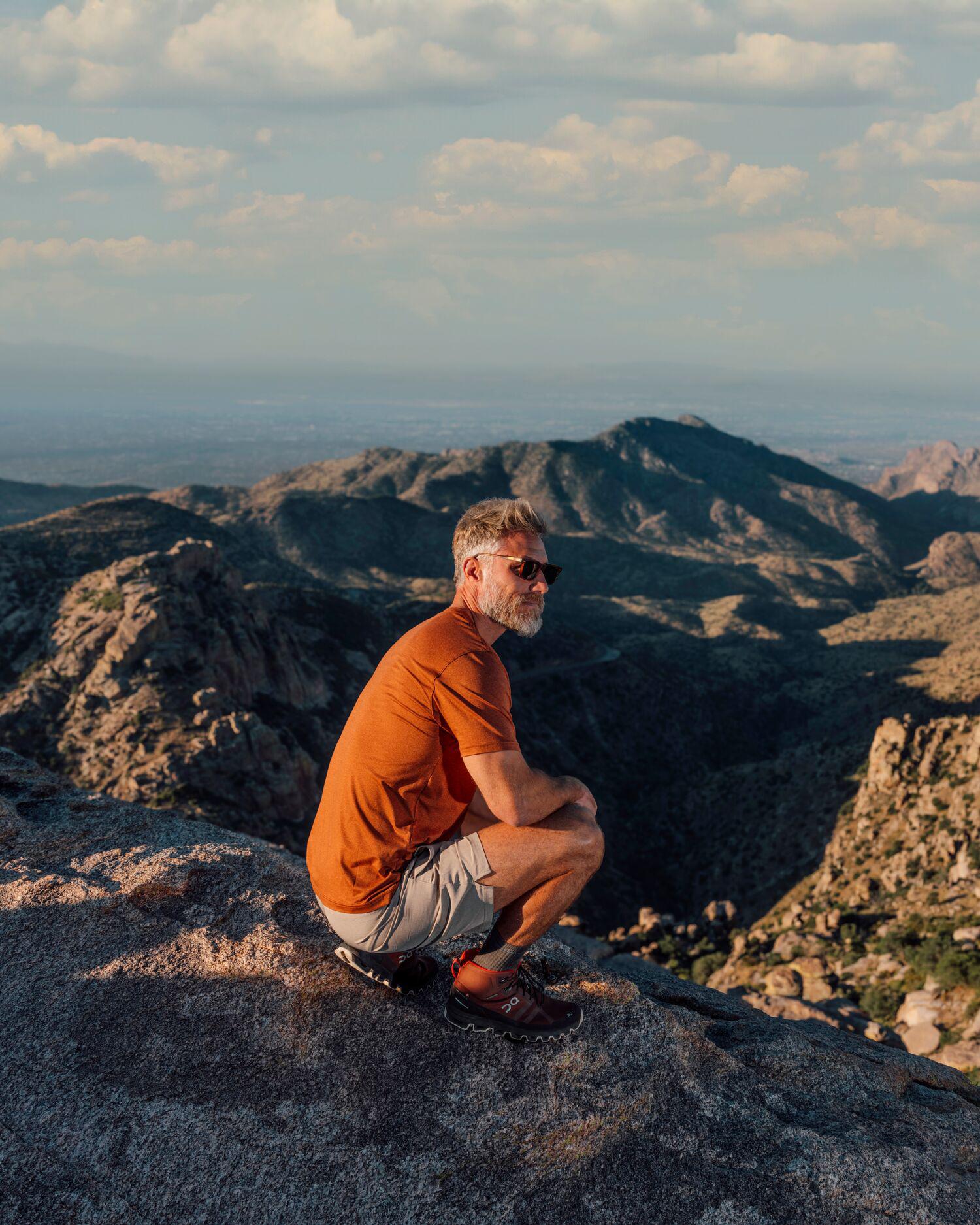 man viewing desert from mountaintop 
