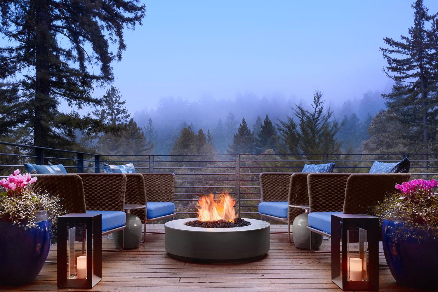 Four chairs surrounding the a firepit at dusk on the deck at Canyon Ranch Woodside.