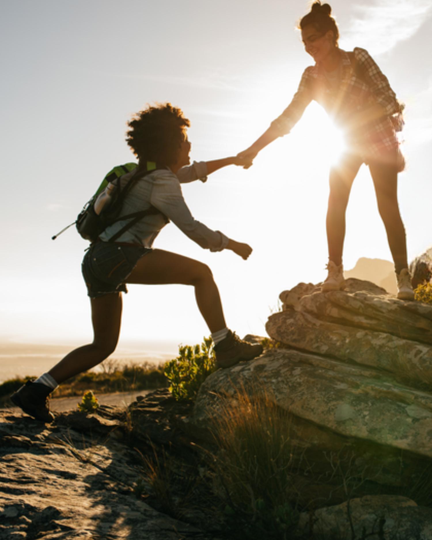 Women climbing a rock on a hike