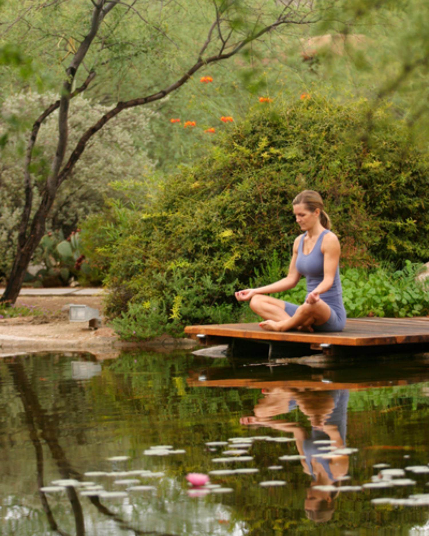 A woman sitting by the pond meditating at Canyon Ranch Tucson health spa resort