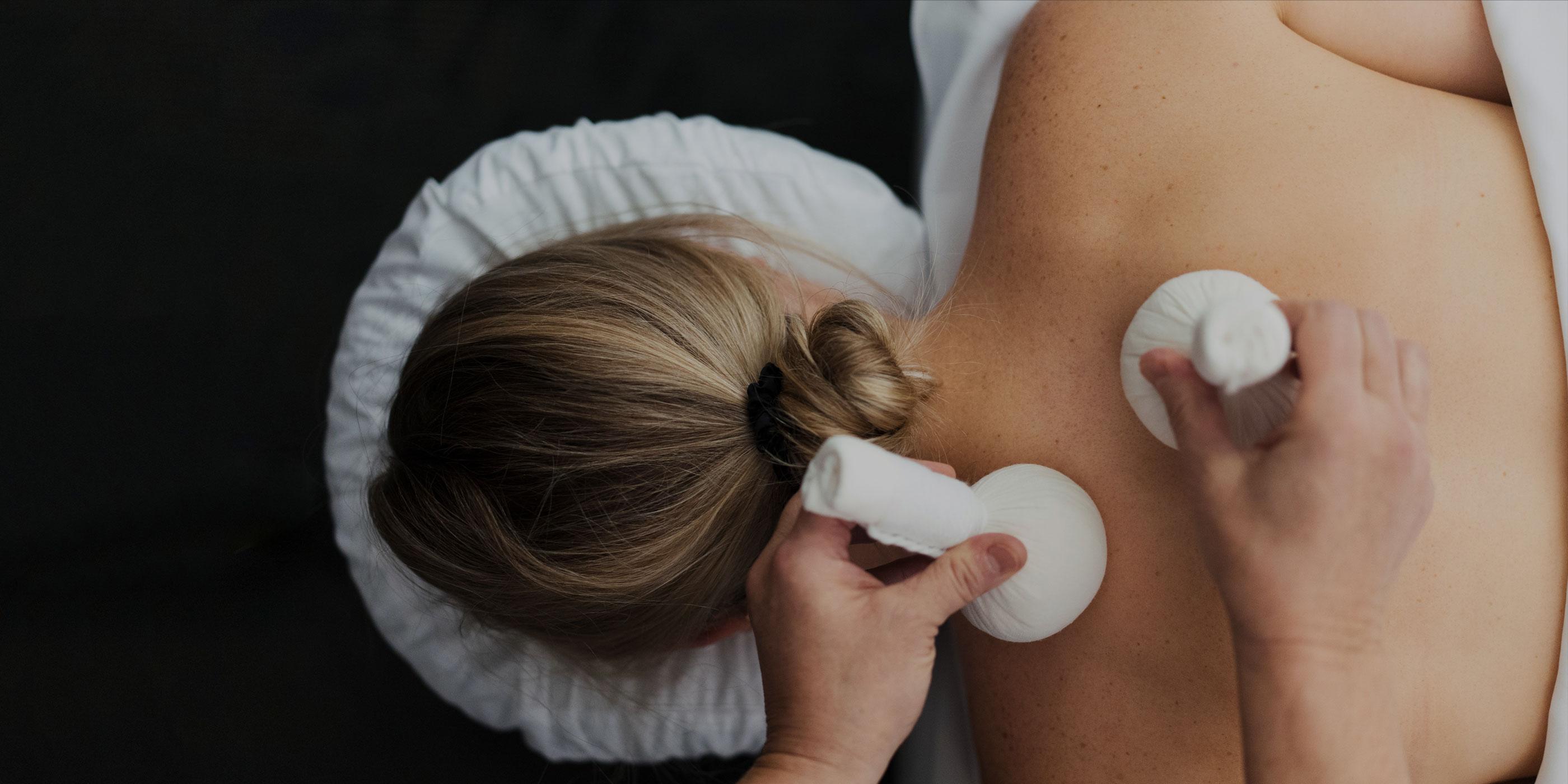 Overhead view of a woman receiving a body treatment with two poultices at on her back at Canyon Ranch.