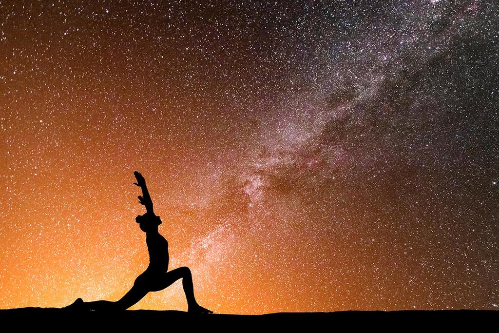A woman doing yoga under the stars