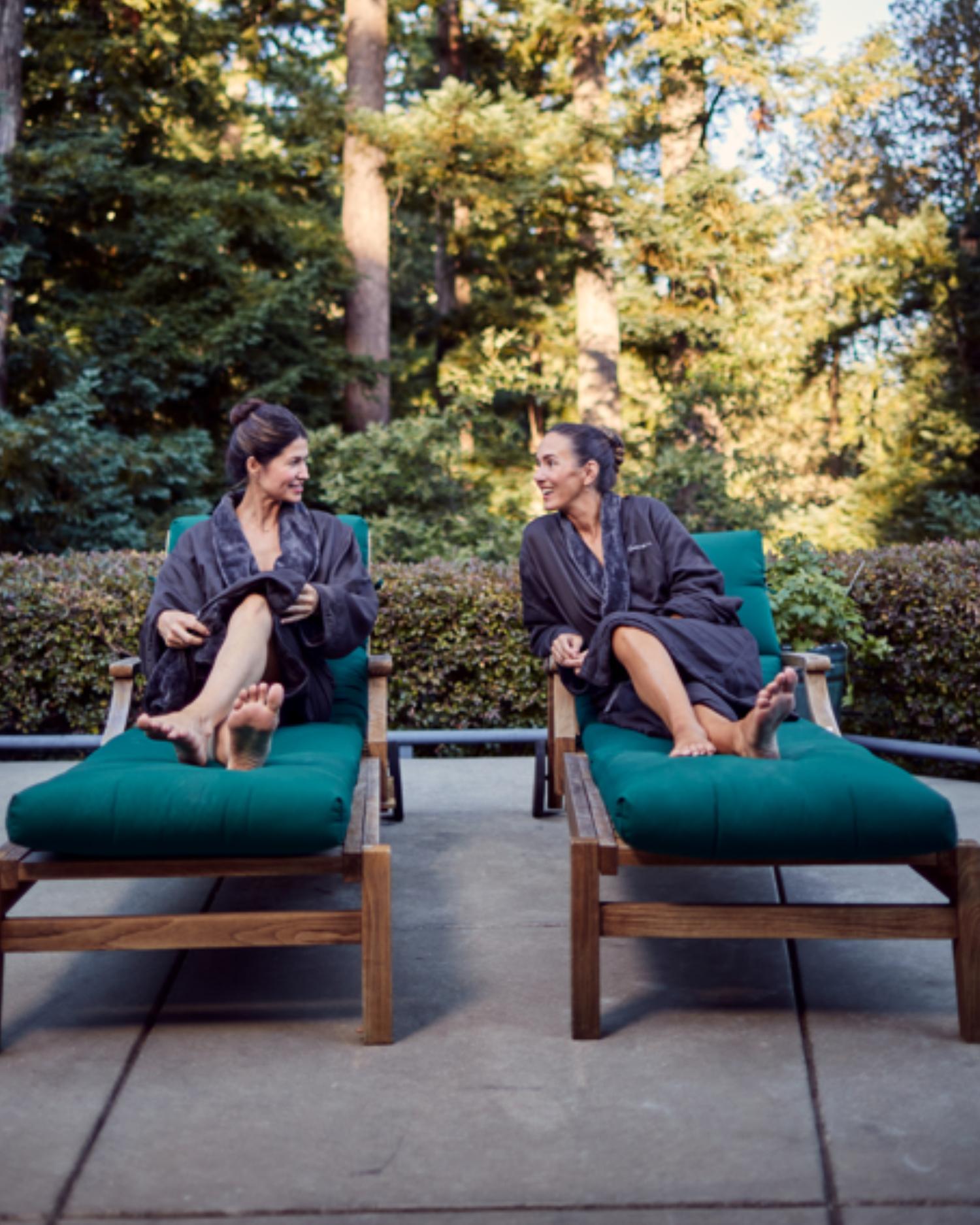 Women sitting on chaise lounges on an outdoor patio in the redwood forest