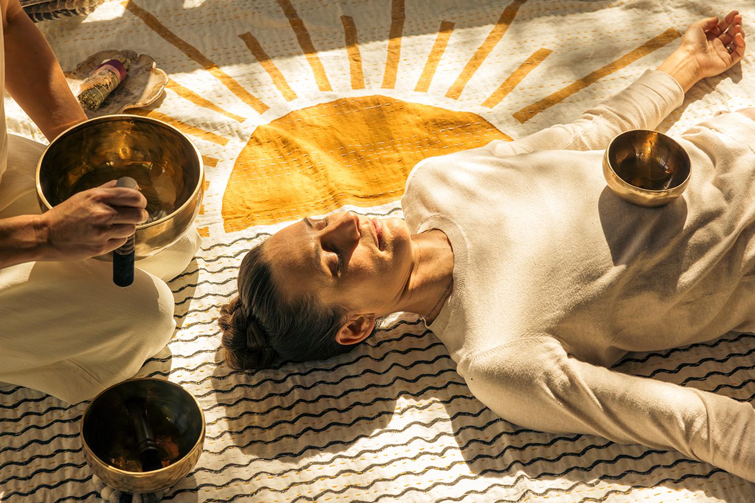 a woman listening to brass sound bowls