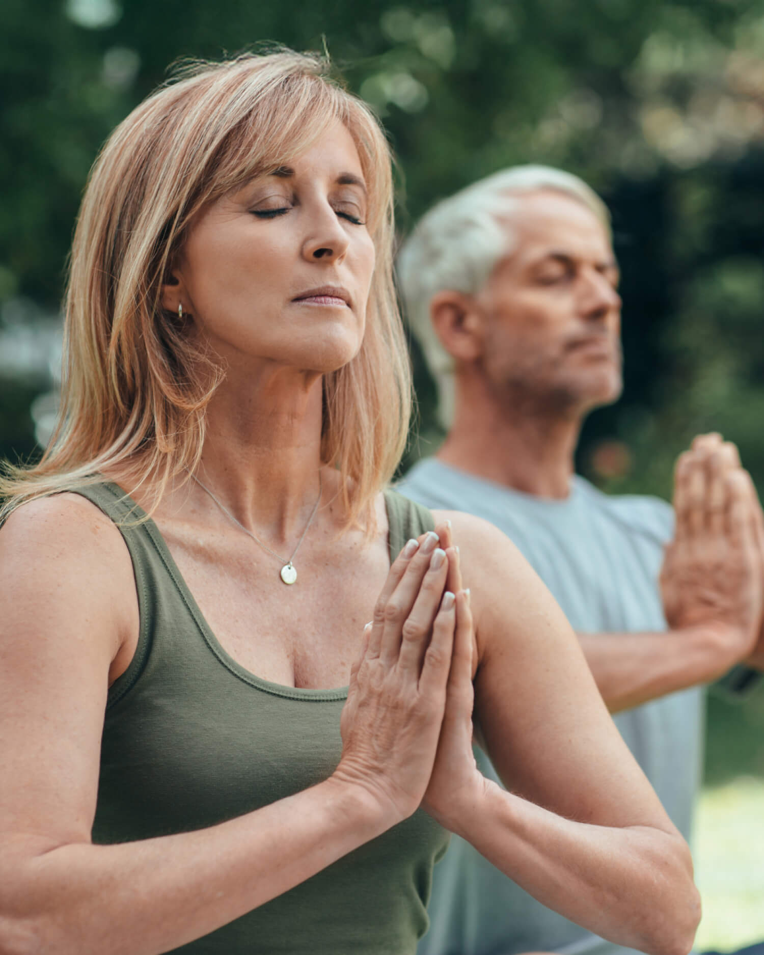 A man and a woman meditating outdoors