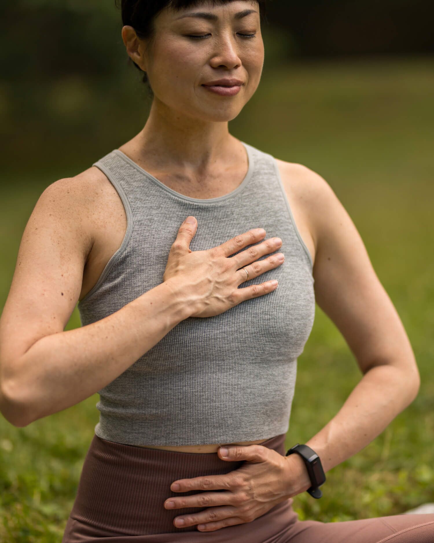 A woman meditating with a fitness tracker