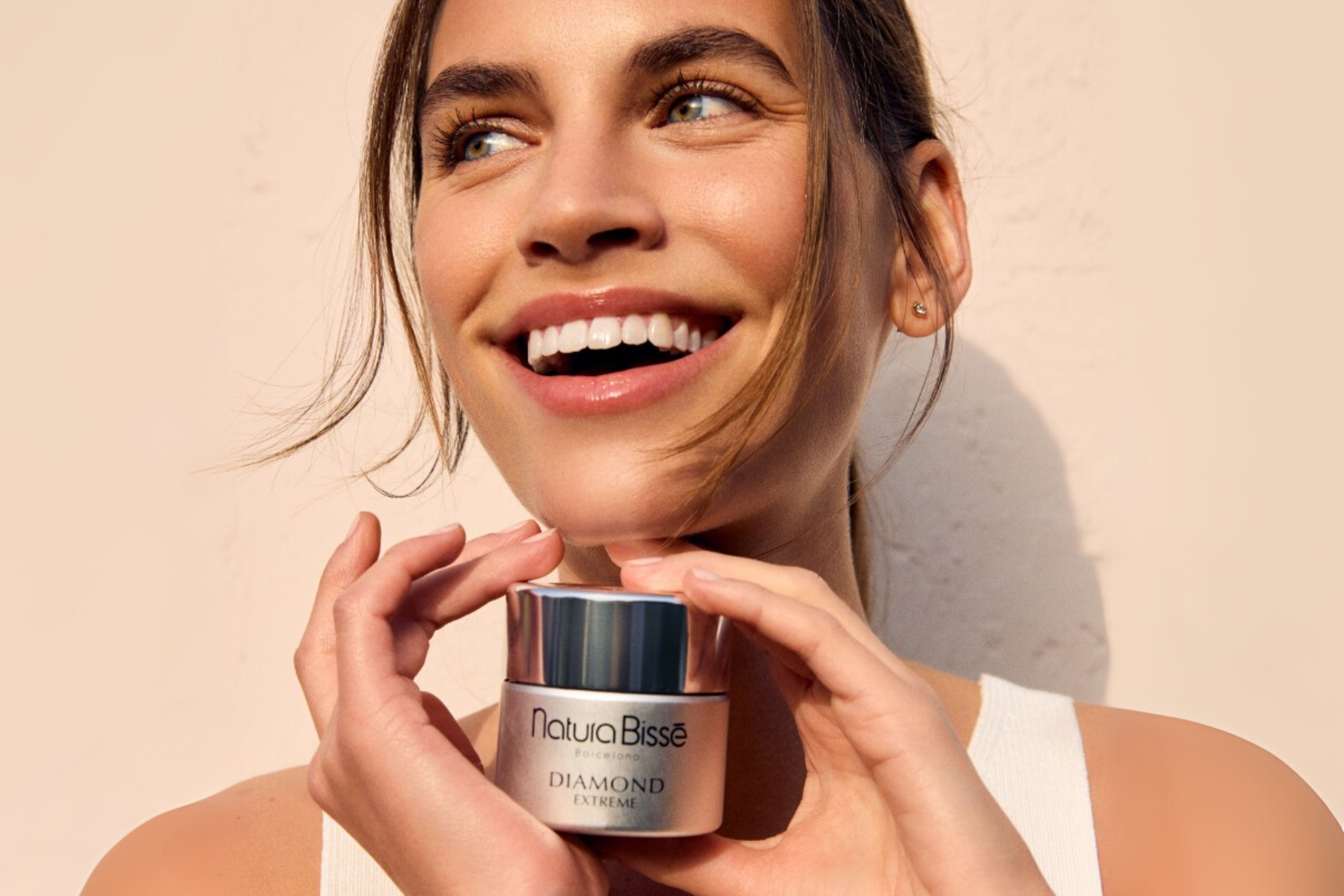 A woman smiling holding a jar of face moisturizer