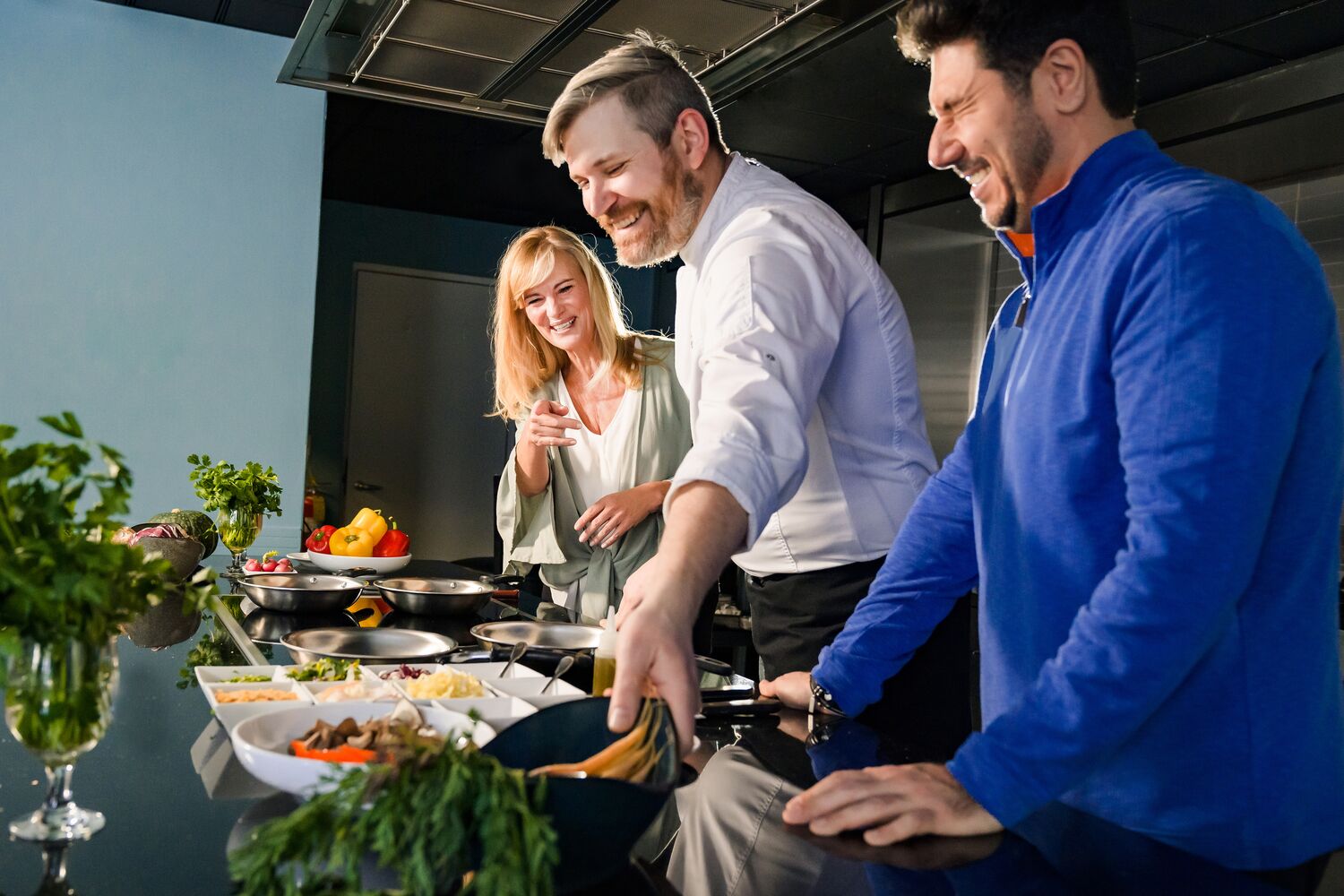 Guests and Chef Cooking in Demo Kitchen.