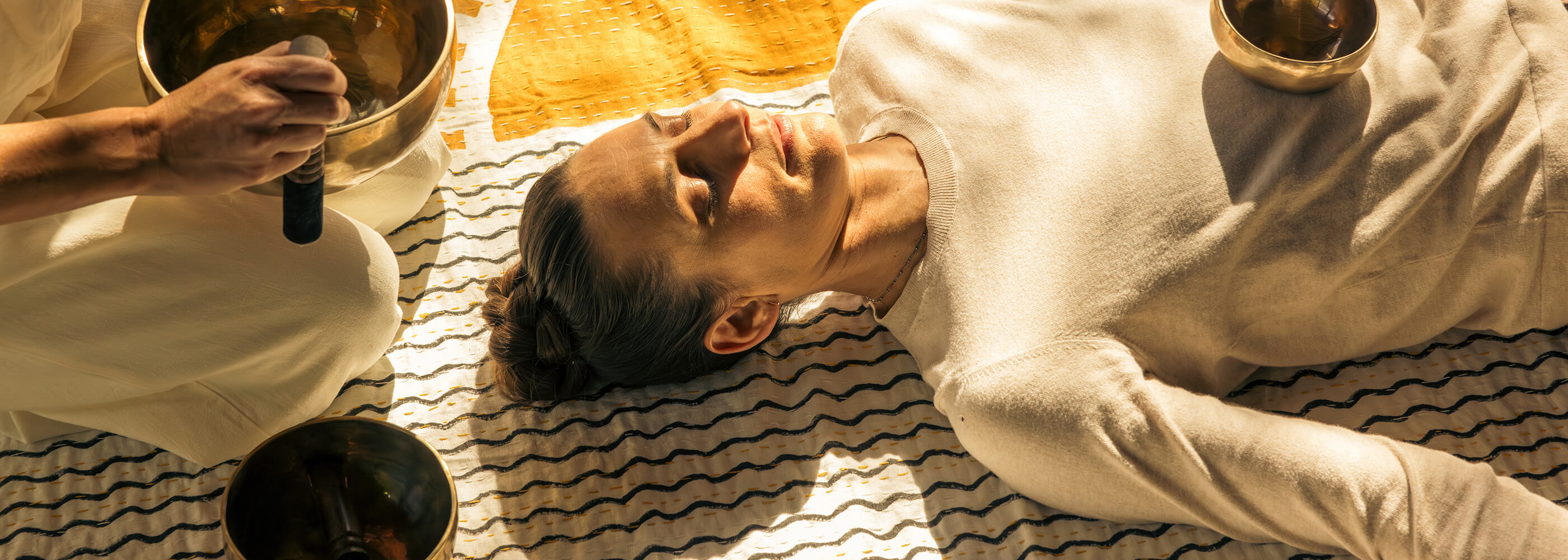 A woman sitting on a wall at sunrise meditating