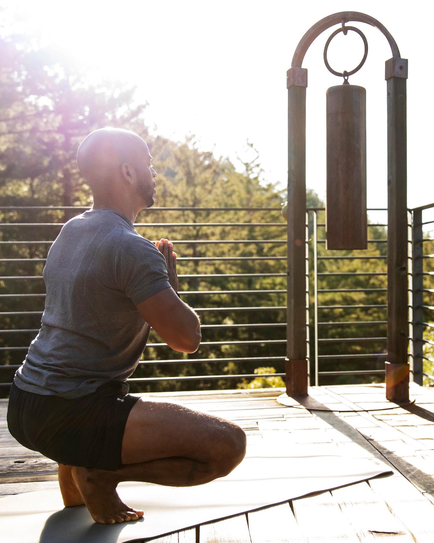Image of man meditating on deck overlooking Redwood trees at a yoga retreat hosted by Canyon Ranch Woodside Fitness + Spa Resort