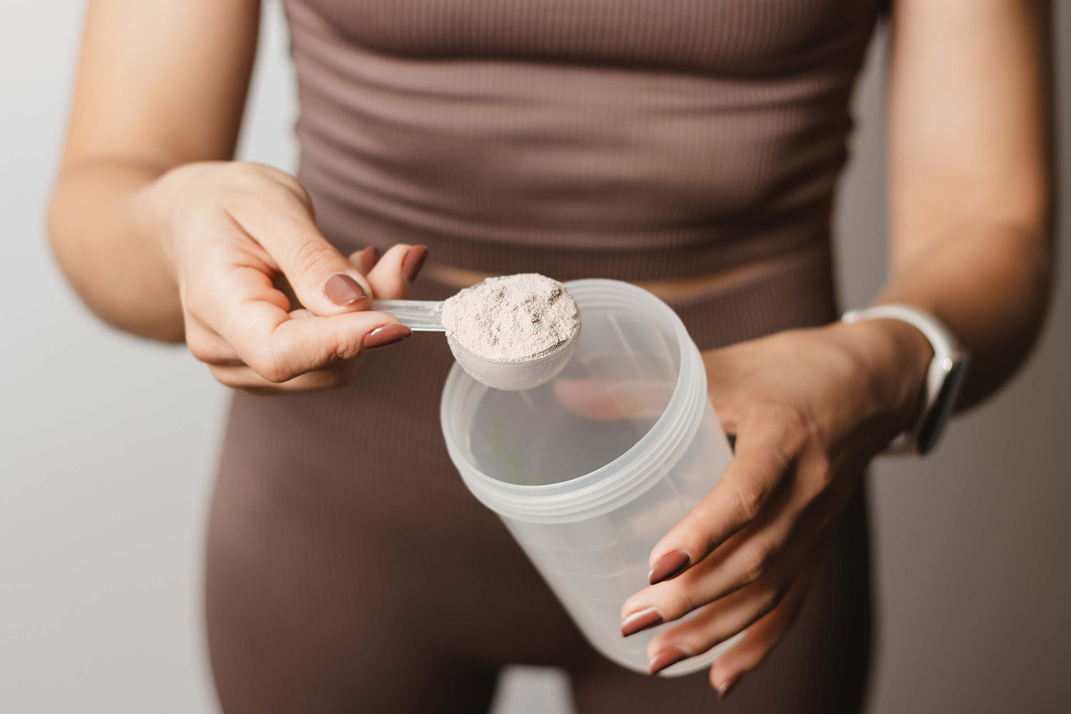 a woman scooping powder into a cup