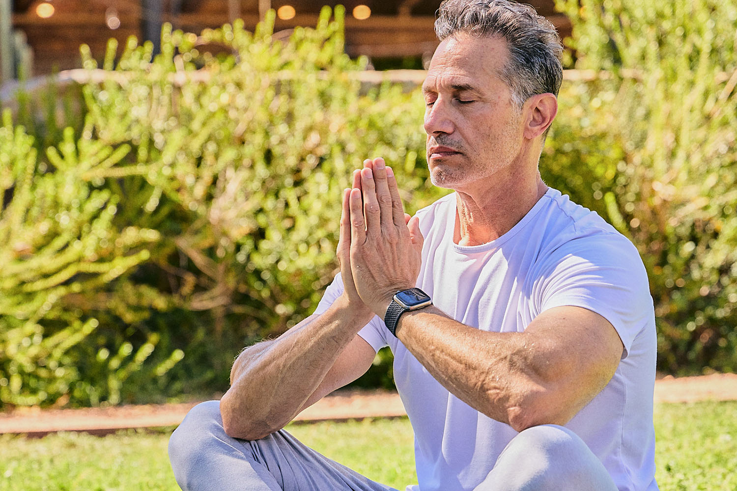 An older woman spreading her arms under a blue sky