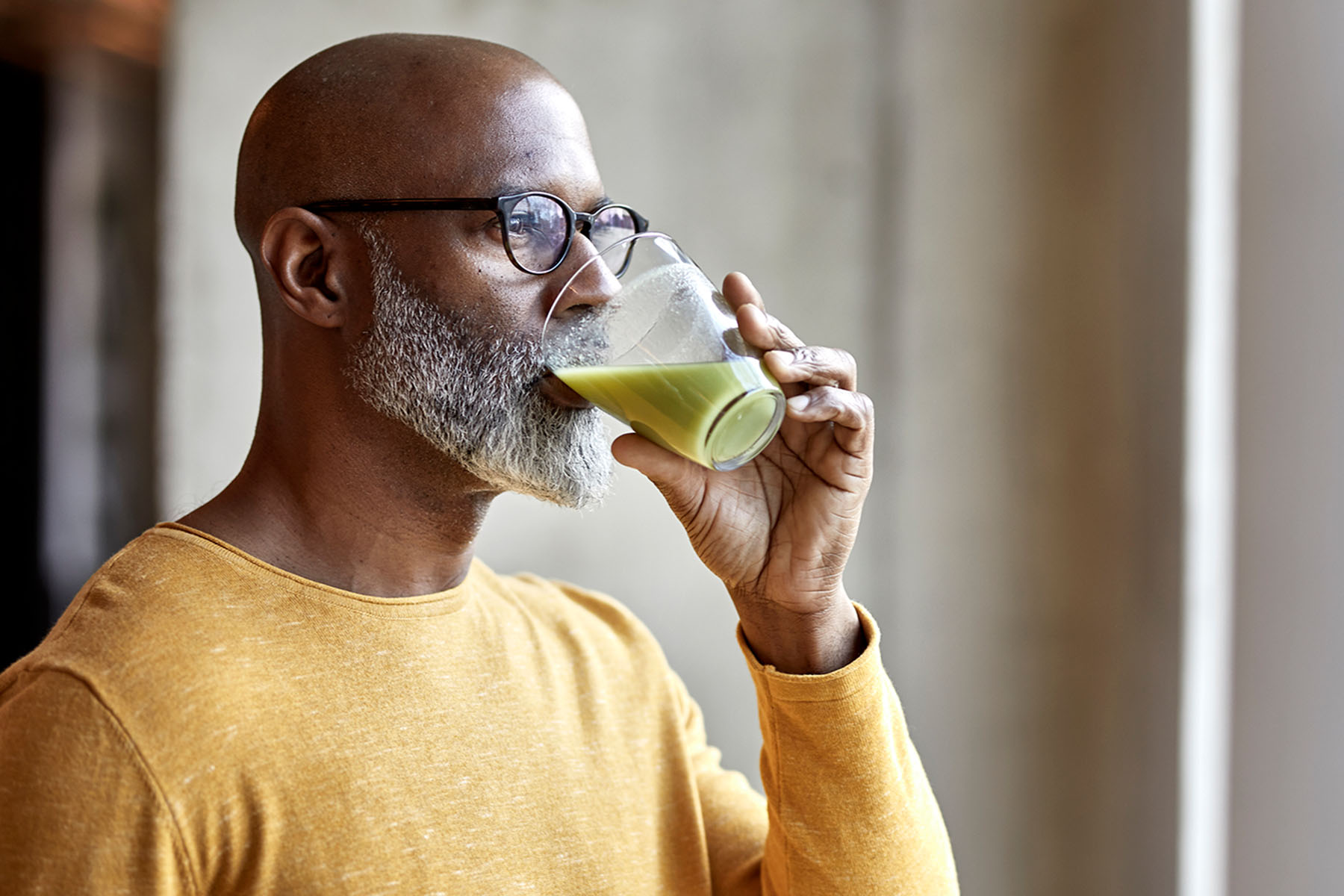 A man drinking a green health smoothie