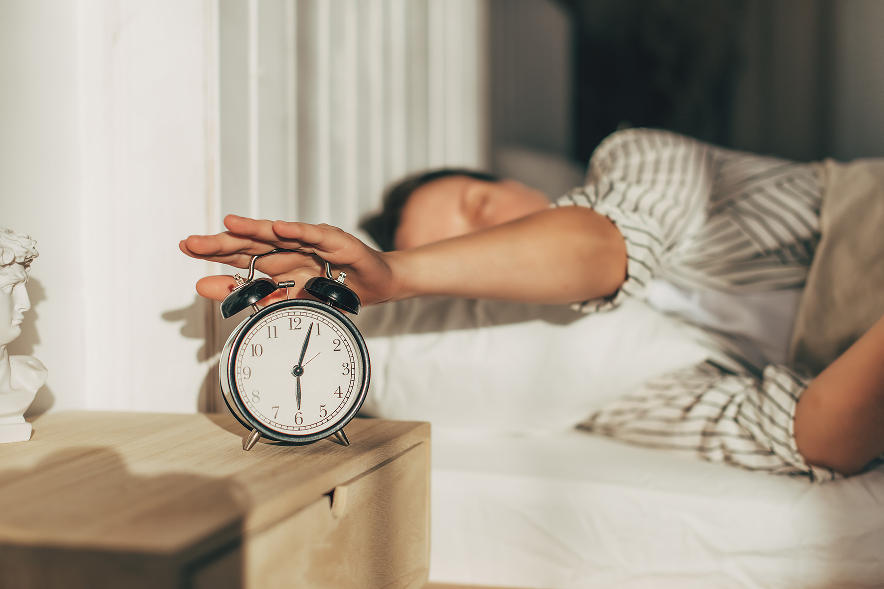 a woman turning off an alarm clock