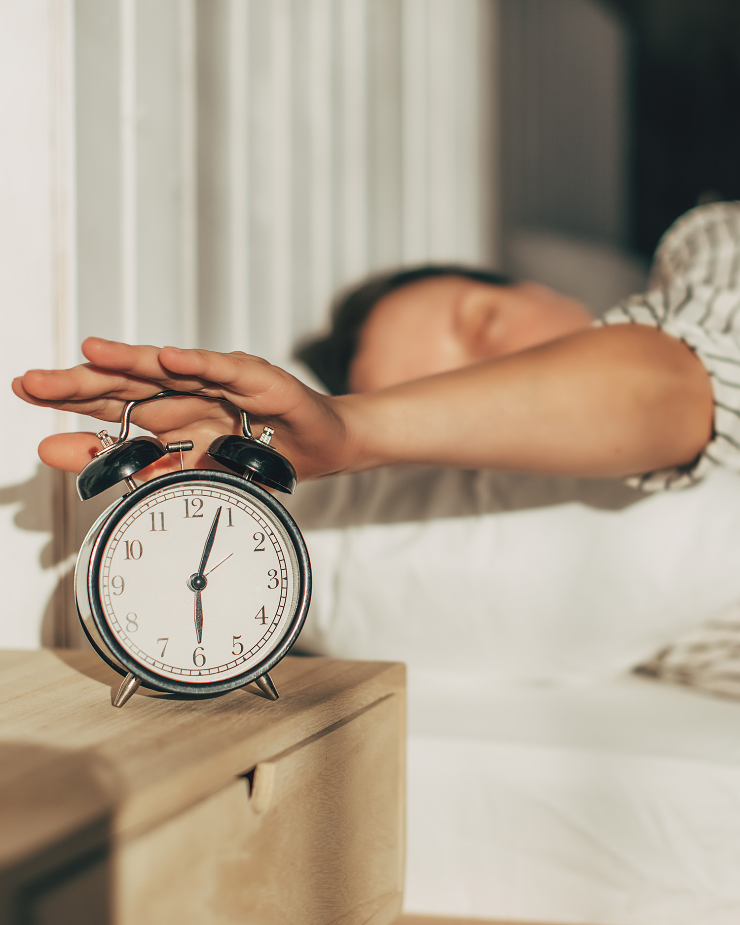 a woman turning off an alarm clock