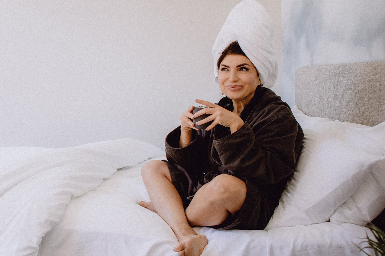 a woman drinking coffee in bed