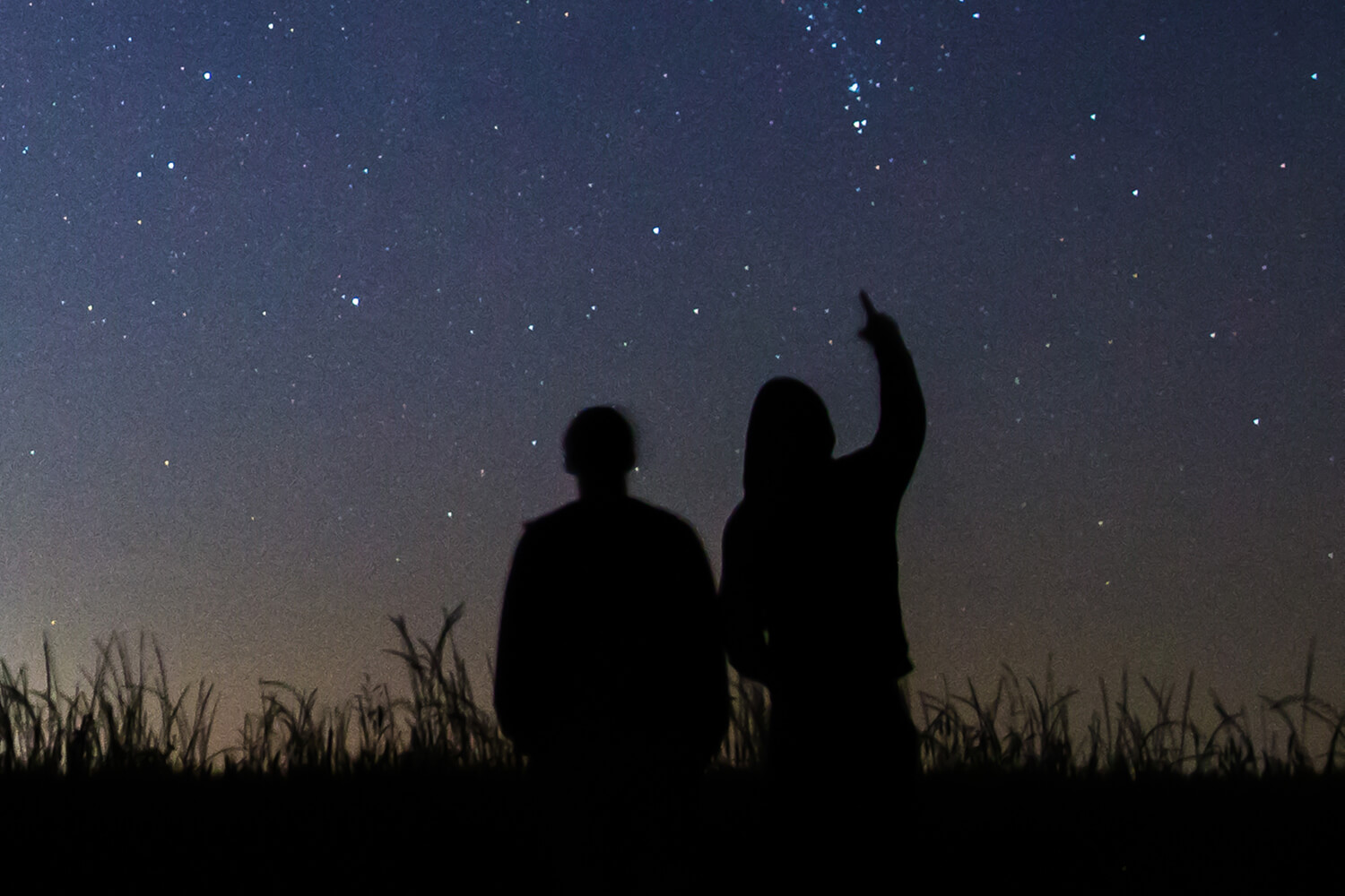 A man and woman looking at stars in the night sky