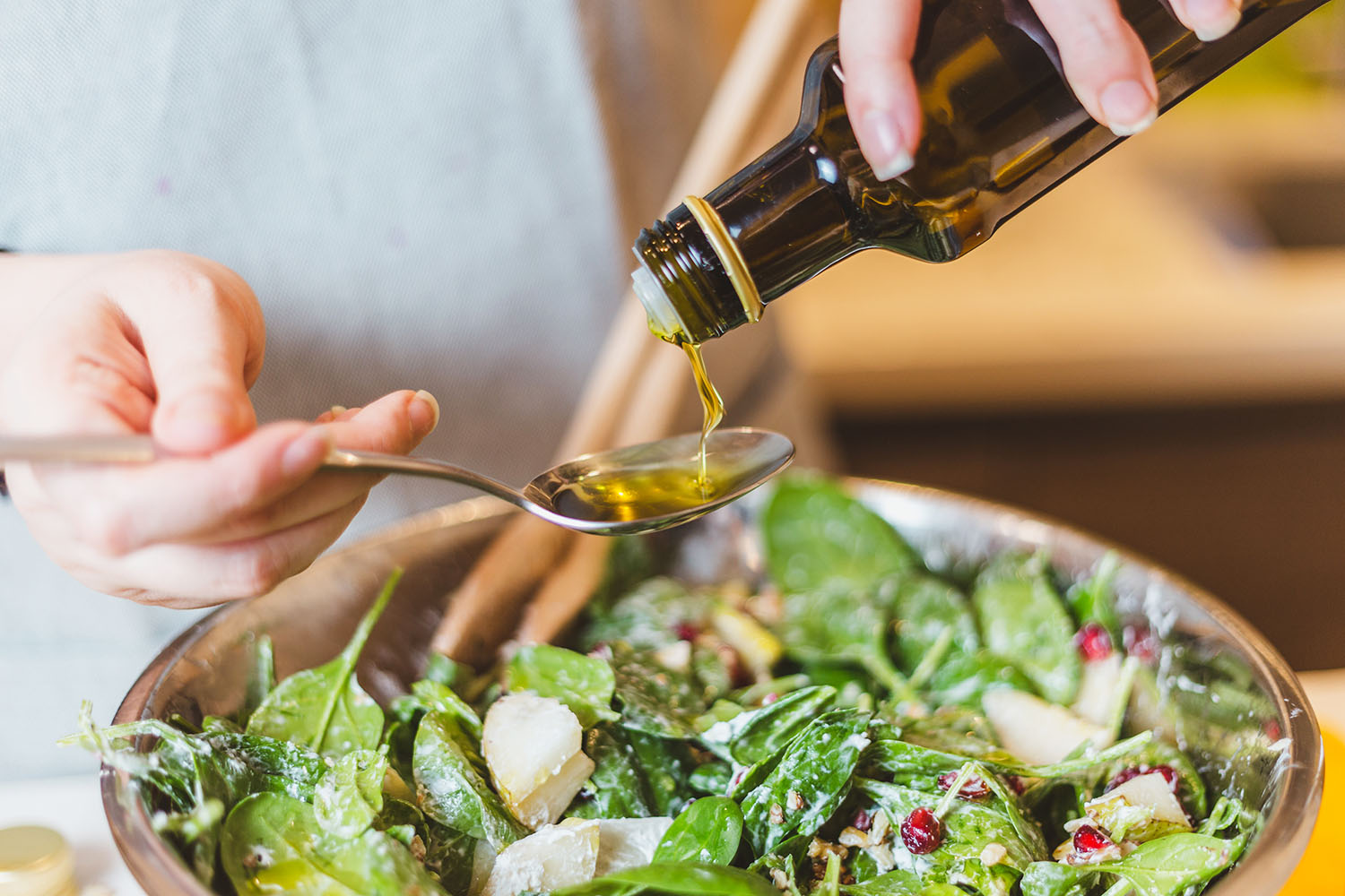 a woman putting dressing on a salad
